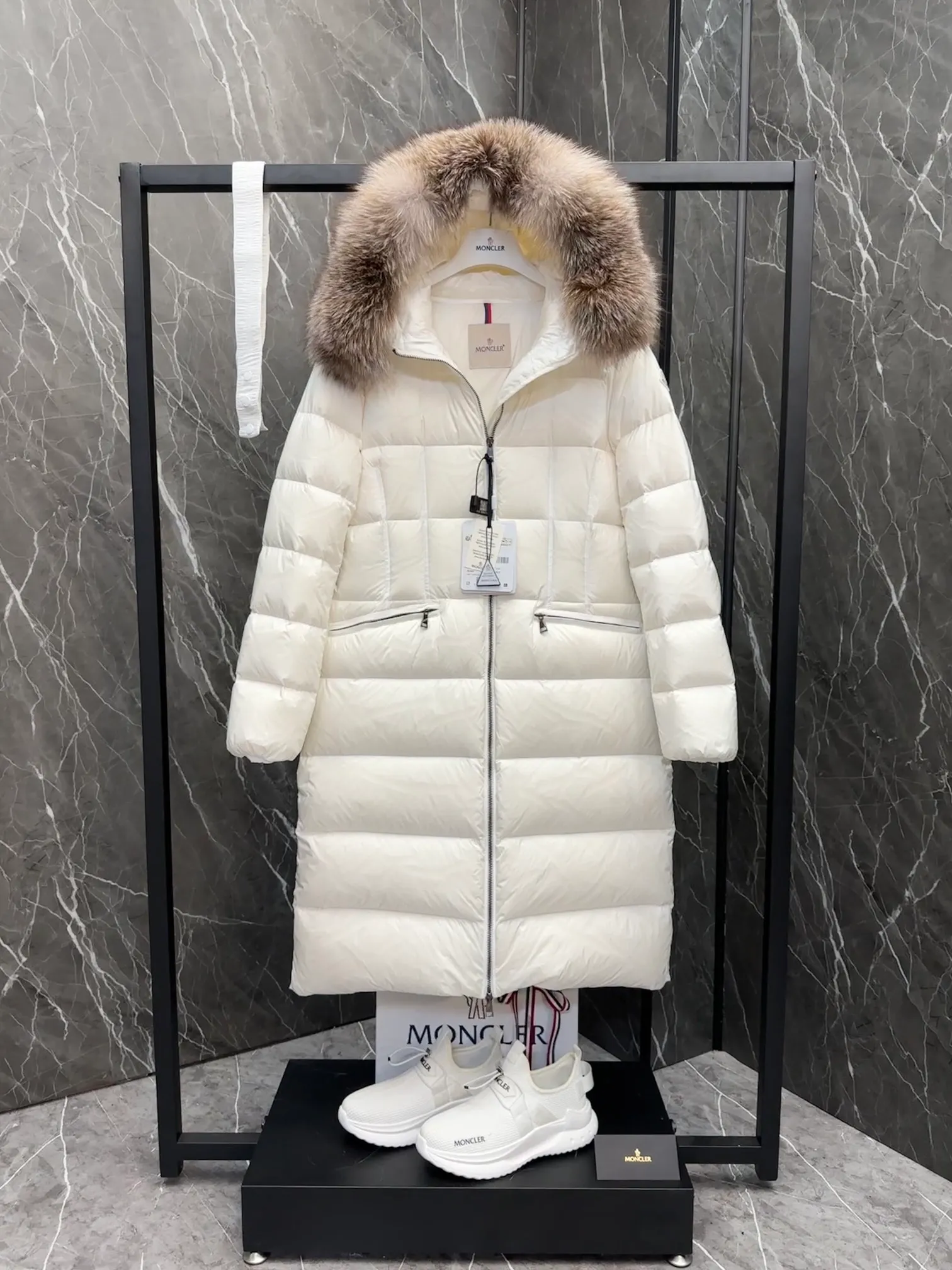 P1020 Moncler Boedic long down jacket for women. (Classic fox fur collar) adopts a whole fox fur collar imported from Finland. The Boedic long down jacket combines exquisite materials and attention to details. The timeless and elegant fashion design can provide you with a warm and caring wearing experience.  Boedic's long down jacket features a waist-cinching belt to accentuate its feminine silhouette for a stylish winter look. The cozy hood has rich fleece trim and is easily removable to suit your mood and weather conditions. Details •Made from lounge saison fabric •Longue saison lining •Filled with down •Hood with removable fox fur collar trim •Two-way zip closure •Elastic waistband with snap button closure •Zip pockets with grosgrain detail •Elastic cuffs Size : 1-4