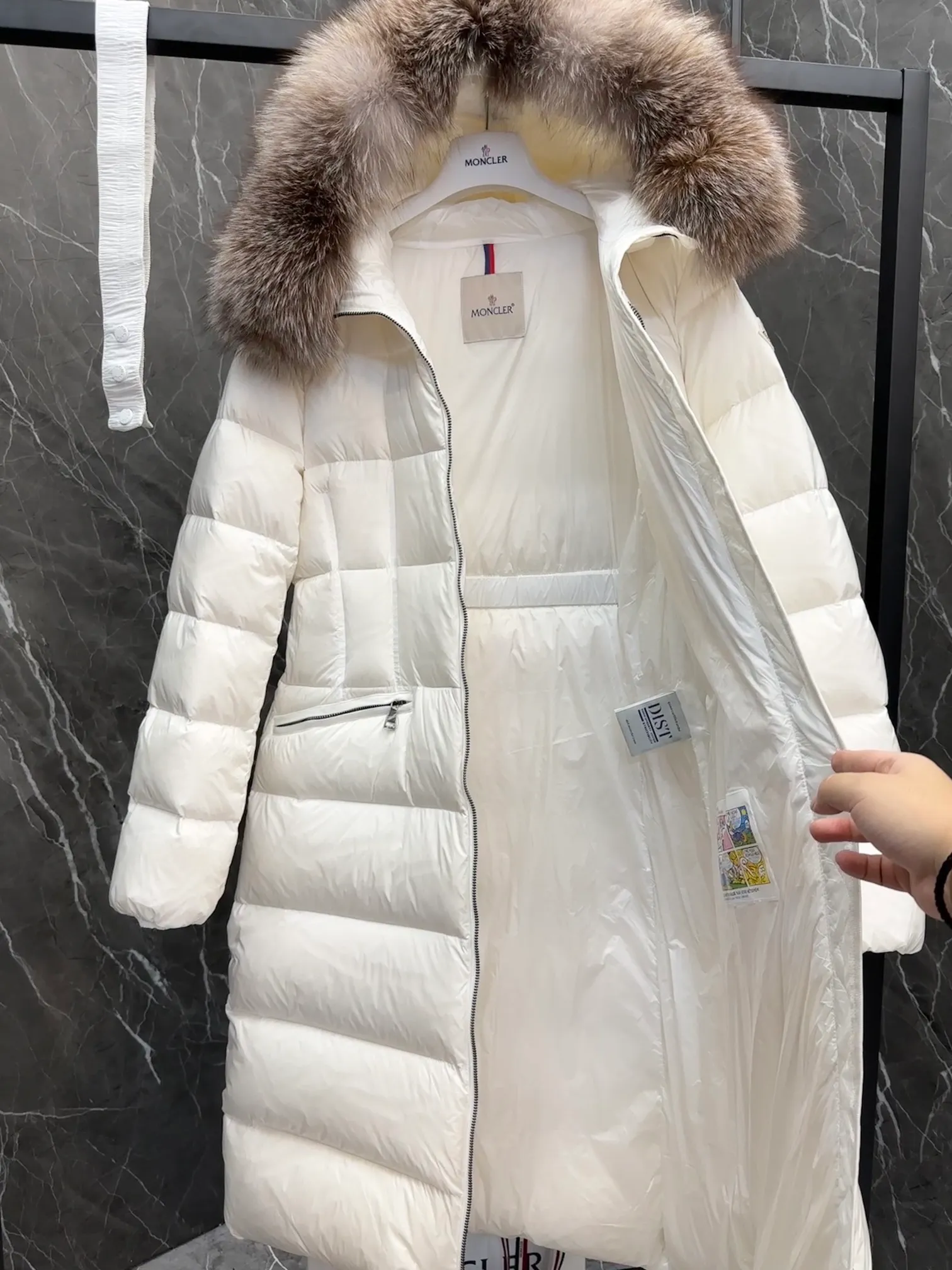 P1020 Moncler Boedic long down jacket for women. (Classic fox fur collar) adopts a whole fox fur collar imported from Finland. The Boedic long down jacket combines exquisite materials and attention to details. The timeless and elegant fashion design can provide you with a warm and caring wearing experience.  Boedic's long down jacket features a waist-cinching belt to accentuate its feminine silhouette for a stylish winter look. The cozy hood has rich fleece trim and is easily removable to suit your mood and weather conditions. Details •Made from lounge saison fabric •Longue saison lining •Filled with down •Hood with removable fox fur collar trim •Two-way zip closure •Elastic waistband with snap button closure •Zip pockets with grosgrain detail •Elastic cuffs Size : 1-4