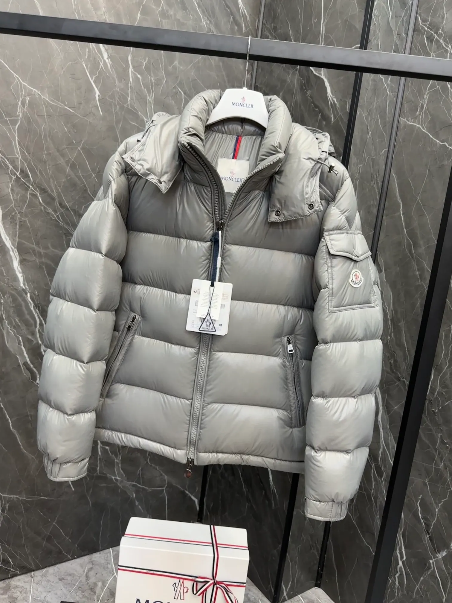 P700 Premium Down ⬆️Moncler Maya classic short down jacket. ⚠️Limited to gray, the only matching color on the market, filled with premium goose down. Try this color on, I guarantee you won’t be able to take it off, it’s too high-end. The Moncler Maya short down jacket is a classic Moncler item, and its style is highly recognizable. Made of lacquered nylon and available in a variety of colors, it's a stylish piece for casual commuting.  The Moncler Maya men's down jacket in shiny patent nylon with signature rectangular quilting is the epitome of Moncler style. A classic cropped design that transcends seasons and styles, it features a statement silhouette, removable hood and adjustable hem. The cuffs are embellished with classic patch pockets, showcasing the brand's signature style. Details • Made of patented nylon • Lacquered nylon lining • Filled with down, rectangular quilting • Detachable hood with snap buttons and drawstring adjustment • Two-way zipper fly • External and internal zippered pockets • Adjustable elastic cuffs with press studs • Drawstring on hood • Flap patch pockets on sleeves • Moncler felt logo on sleeves Size: 1-8 Premium Gray Couple Style.