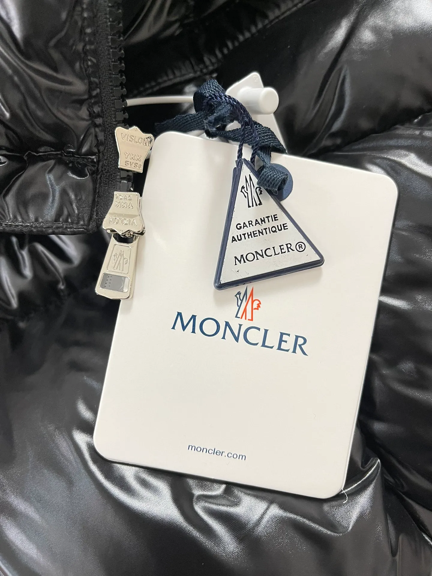 P1180 Moncler Montbeliard glossy down jacket The Montbeliard down jacket is made of shiny patent nylon and features highly recognizable rectangular quilting. Featuring a hooded design and signature patch pocket at chest.  Fabric: 100% nylon Filling content: 90% white goose down 250-300g Craftsmanship: Made of nylon laqué fabric Nylon laque lining Filled with down, detachable and adjustable hood with drawstring closure Built-in flap with webbing, black pocket details at the lower end Zipper closure Collar with snap buttons Zipper pockets Patch pockets with snap buttons Adjustable cuffs Adjustable elastic drawstring hem.  Size: 1 2 3 4 5 0548000