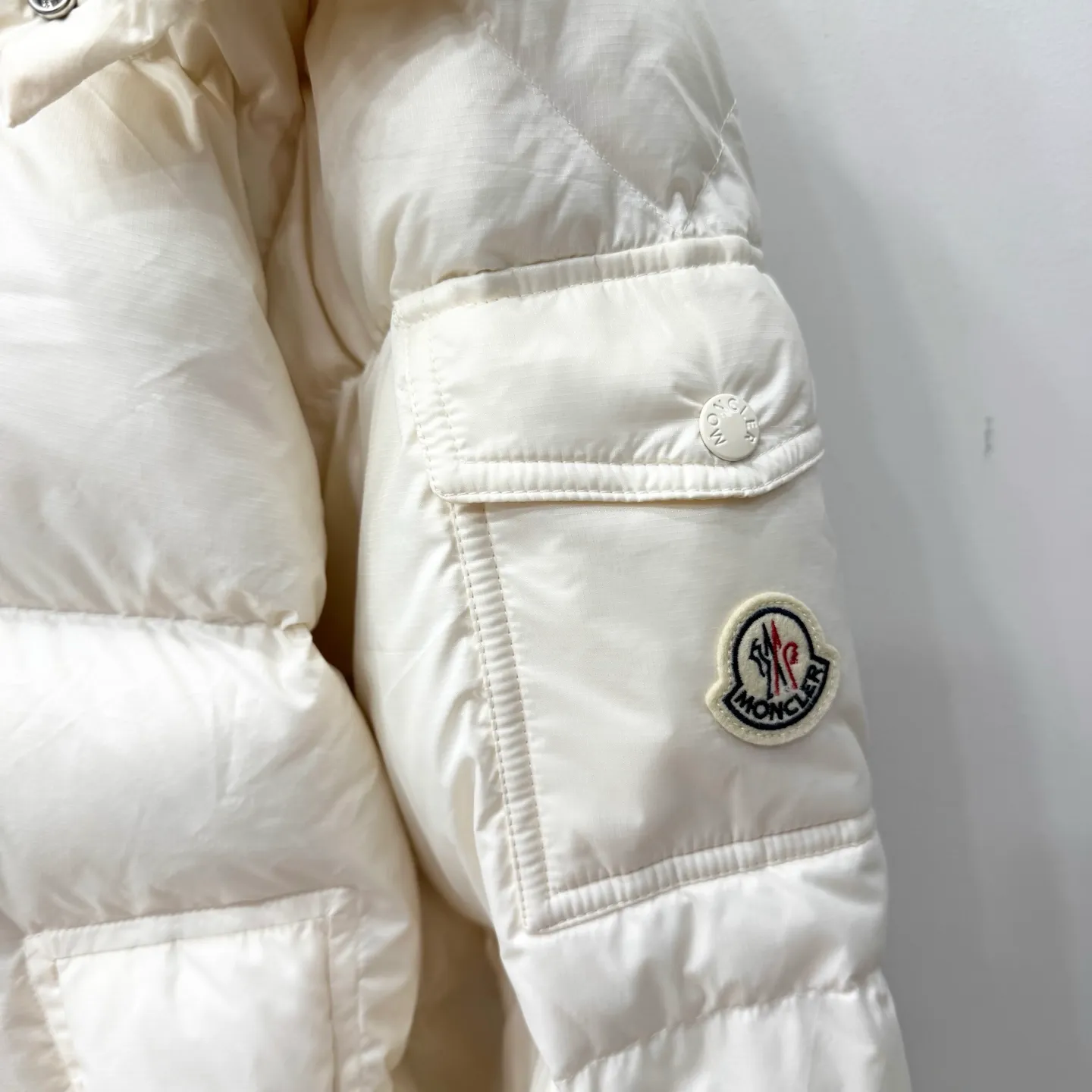 P1100 Brand: Moncler Filling: 90 white duck down Weight: 380-450 Color: White Black Gray Size: 12345 [Couyere Men's Hooded Short Down Jacket] The Couyere short down jacket is durable and practical, provides functional warmth and care, and will accompany you to meet challenges.  The Couyere is a durable down jacket made from a fine fabric that's durable and functional, with velvet resistance and functionality. The short design creates a sculpted silhouette, and padded pockets add a modern feel. The sleeves are embellished with signature patch pockets, a nod to the classic Moncler Maya down jacket.  • Made of fine ripstop fabric • Fine fabric lining • Down filling • Detachable and adjustable hood • Zip closure • Zippered pockets • Press-studs on sleeve pockets • Elastic cuffs • Drawstring hem Fabric: 100% nylon; Lining: 100% nylon; Filling: Goose down Down content: 90%; except upholstery; Maximum wash temperature 30°C - Mild wash; Do not bleach; Do not tumble dry; Ironing maximum temperature 110°C - without steam; Hydrocarbon dry cleaning - gentle wash; Professional wet cleaning - gentle wash; Lay flat to dry in shade; Wash separately; Remove removable accessories before washing; Recommend washing and ironing inside out