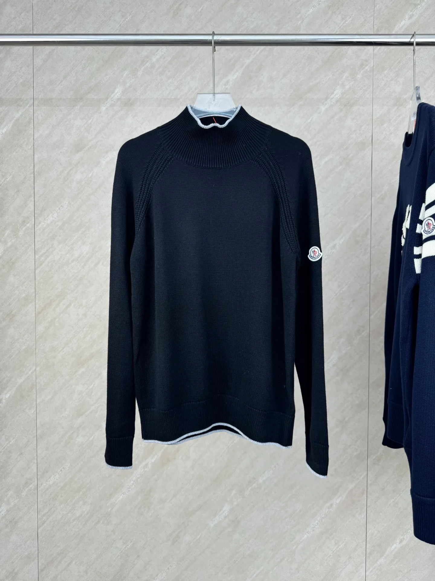 P430 Moncler Mouth Logo High Neck Knitted Long Sleeve Sweater Size: S/M/L/XL The sweater adopts high collar knitting technology, and the neck texture is tight and elastic, which is both warm and stylish. In terms of detailed craftsmanship, hollow knitting splicing technology is used on the shoulders, with fine texture and distinct layers, which enhances the design sense of the body; the contrasting rib technology on the cuffs and hem forms a soft contrast with the main color, improving the overall sophistication; the brand logo on the left arm uses three-dimensional embroidery technology, with precise stitching, highlighting the brand recognition. Made of high-quality knitted fabrics and made with fine weaving technology, it is skin-friendly, comfortable and has a crisp silhouette. From the warm design of the collar to the details of the embroidery, every craftsmanship reflects the brand's dual pursuit of quality and fashion. It is an autumn and winter item that combines practicality and design. Purchase the original version for development, order the color and dye it, and feel free to compare it with any version on the market!