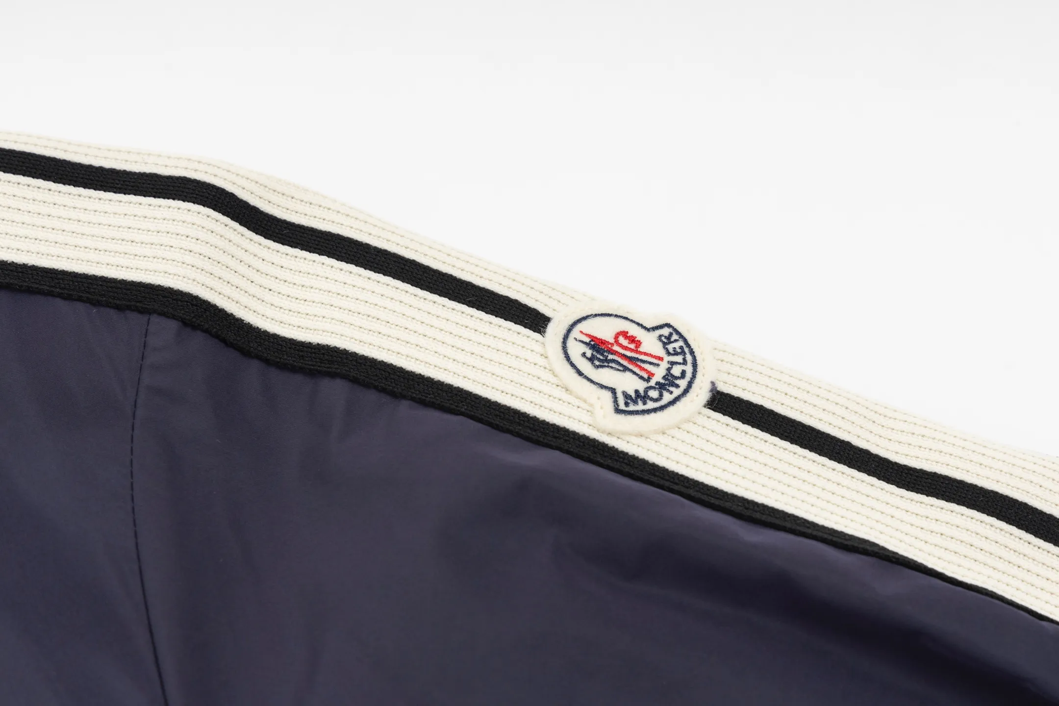 P550 Exclusive supply] Moncler Webbing Armband Lightweight Jacket (Navy Blue) The fabric is made of 100% polyester fiber to create a tough protective outer layer. It is known for its excellent tear resistance and wear resistance. It can quickly return to flatness during wearing and maintain the crisp and stylish appearance of the clothing for a long time. At the same time, it is not easy to deform after being washed for a long time. Decorative edging in two different colors has been added to the center section of the sleeves. This design element not only adds visual highlights to the clothing, making it more fashionable and unique, the webbing is precisely positioned along the specified contours from the cuffs to the seam of the collar to ensure symmetry and overall smoothness. Before actual sewing, use very fine basting stitches for pre-fixing. This step is crucial to prevent the webbing from slipping, twisting, or wrinkling during sewing and ensuring that the final stitch is straight and perfect. Size:1/2/3/4