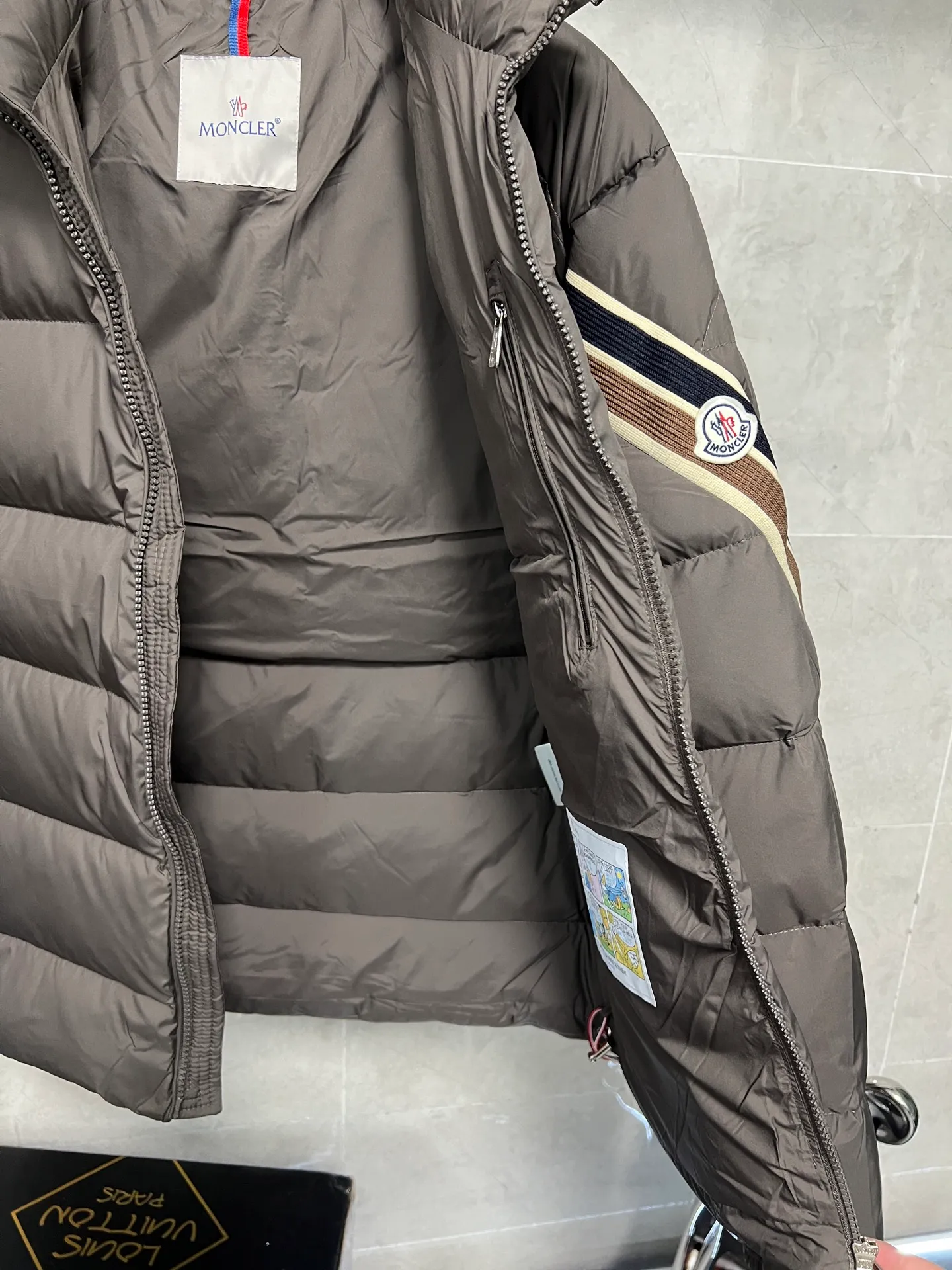 P880 MonclerSolayan men's short down jacket is decorated with seasonal iconic stripe details, blending sportsmanship and timeless style. Solayan down is made of micro chic fabrics and has a tough square shape design, highlighting Moncler's sportsmanship. This cropped style features tricolor stripes on the sleeves for a seasonal interpretation of the brand's signature. Comes with a practical pull-out hood. Color: Black Dark Brown Size: 12345