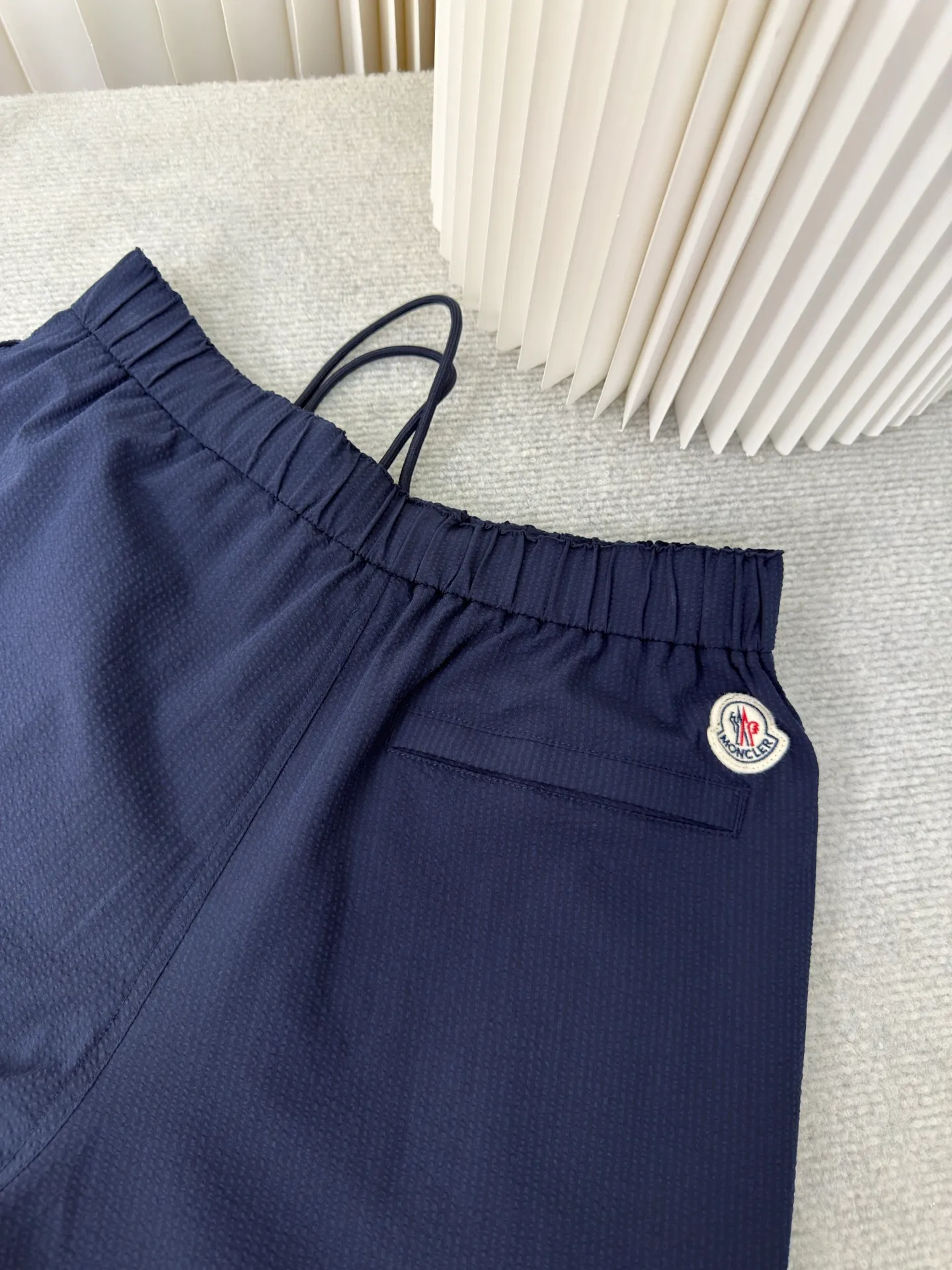 P410 MONCLER Puff Wrinkle Pants with Mouth, Authentic Open Version - Physical Counter - Top Luxury Quality 🆚Second Price of All Versions on the Market Made of cotton blended woven fabric with 76% high cotton content + 24% polyester fiber. The high cotton content ensures that the fabric is soft, skin-friendly, and has good breathability. The addition of a small amount of polyester fiber balances the wrinkle resistance and elasticity of the overall fabric and greatly reduces its shrinkage. After preshrinking, dimensional changes during washing are negligible. The fusion of the two makes the fabric combine anti-wrinkle, quick-drying, easy care and other characteristics without losing the advantages of good wearing experience and strong breathability.  The ground warp + bubble warp is independently let-off. The bubble warp yarn feeding speed is about 20% higher than the ground warp yarn feeding speed. During weaving, the bubble warp is relaxed and accumulated, forming a naturally arched bubble unit. Through the alternating arrangement of yarns and the change of floating tissue, a clear grid frame is built between the bubble units. Finally, the bubble three-dimensional effect and grid outline are locked through high-temperature heat setting. Size:1 2 3 4