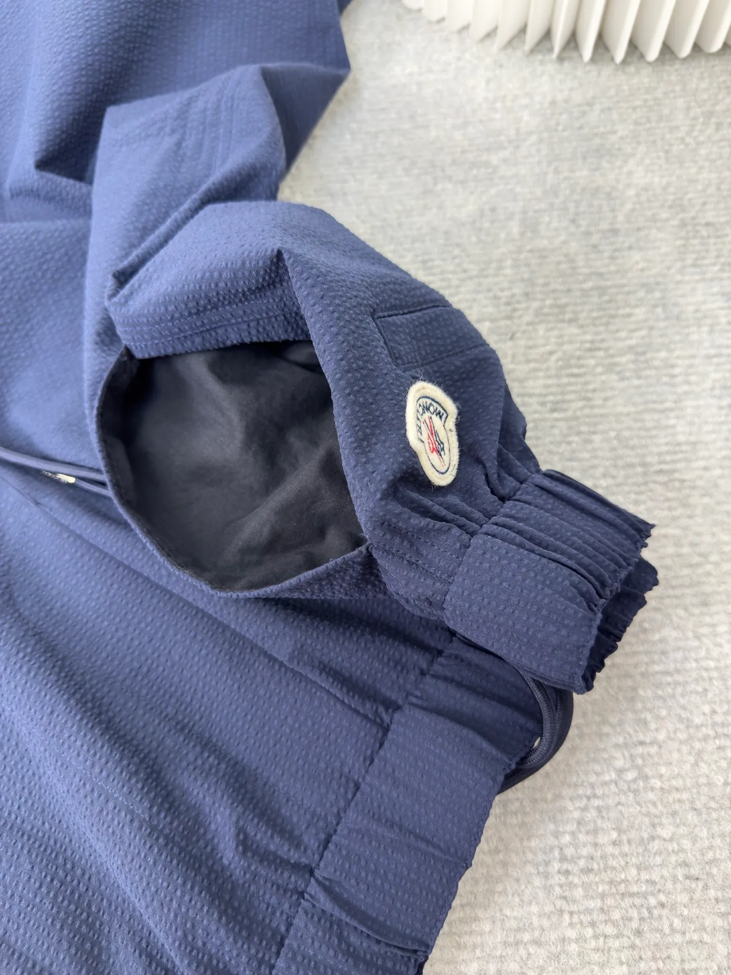 P410 MONCLER Puff Wrinkle Pants with Mouth, Authentic Open Version - Physical Counter - Top Luxury Quality 🆚Second Price of All Versions on the Market Made of cotton blended woven fabric with 76% high cotton content + 24% polyester fiber. The high cotton content ensures that the fabric is soft, skin-friendly, and has good breathability. The addition of a small amount of polyester fiber balances the wrinkle resistance and elasticity of the overall fabric and greatly reduces its shrinkage. After preshrinking, dimensional changes during washing are negligible. The fusion of the two makes the fabric combine anti-wrinkle, quick-drying, easy care and other characteristics without losing the advantages of good wearing experience and strong breathability.  The ground warp + bubble warp is independently let-off. The bubble warp yarn feeding speed is about 20% higher than the ground warp yarn feeding speed. During weaving, the bubble warp is relaxed and accumulated, forming a naturally arched bubble unit. Through the alternating arrangement of yarns and the change of floating tissue, a clear grid frame is built between the bubble units. Finally, the bubble three-dimensional effect and grid outline are locked through high-temperature heat setting. Size:1 2 3 4