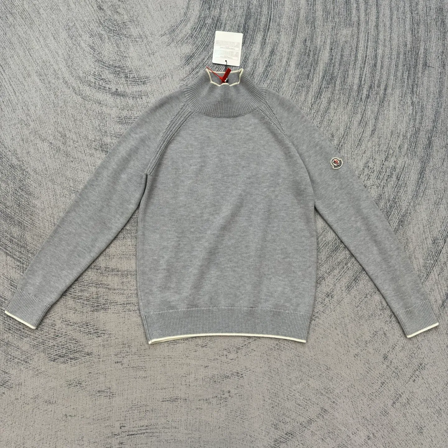 P430 Moncler Mouth Logo High Neck Knitted Long Sleeve Sweater Size: S/M/L/XL The sweater adopts high collar knitting technology, and the neck texture is tight and elastic, which is both warm and stylish. In terms of detailed craftsmanship, hollow knitting splicing technology is used on the shoulders, with fine texture and distinct layers, which enhances the design sense of the body; the contrasting rib technology on the cuffs and hem forms a soft contrast with the main color, improving the overall sophistication; the brand logo on the left arm uses three-dimensional embroidery technology, with precise stitching, highlighting the brand recognition. Made of high-quality knitted fabrics and made with fine weaving technology, it is skin-friendly, comfortable and has a crisp silhouette. From the warm design of the collar to the details of the embroidery, every craftsmanship reflects the brand's dual pursuit of quality and fashion. It is an autumn and winter item that combines practicality and design. Purchase the original version for development, order the color and dye it, and feel free to compare it with any version on the market!