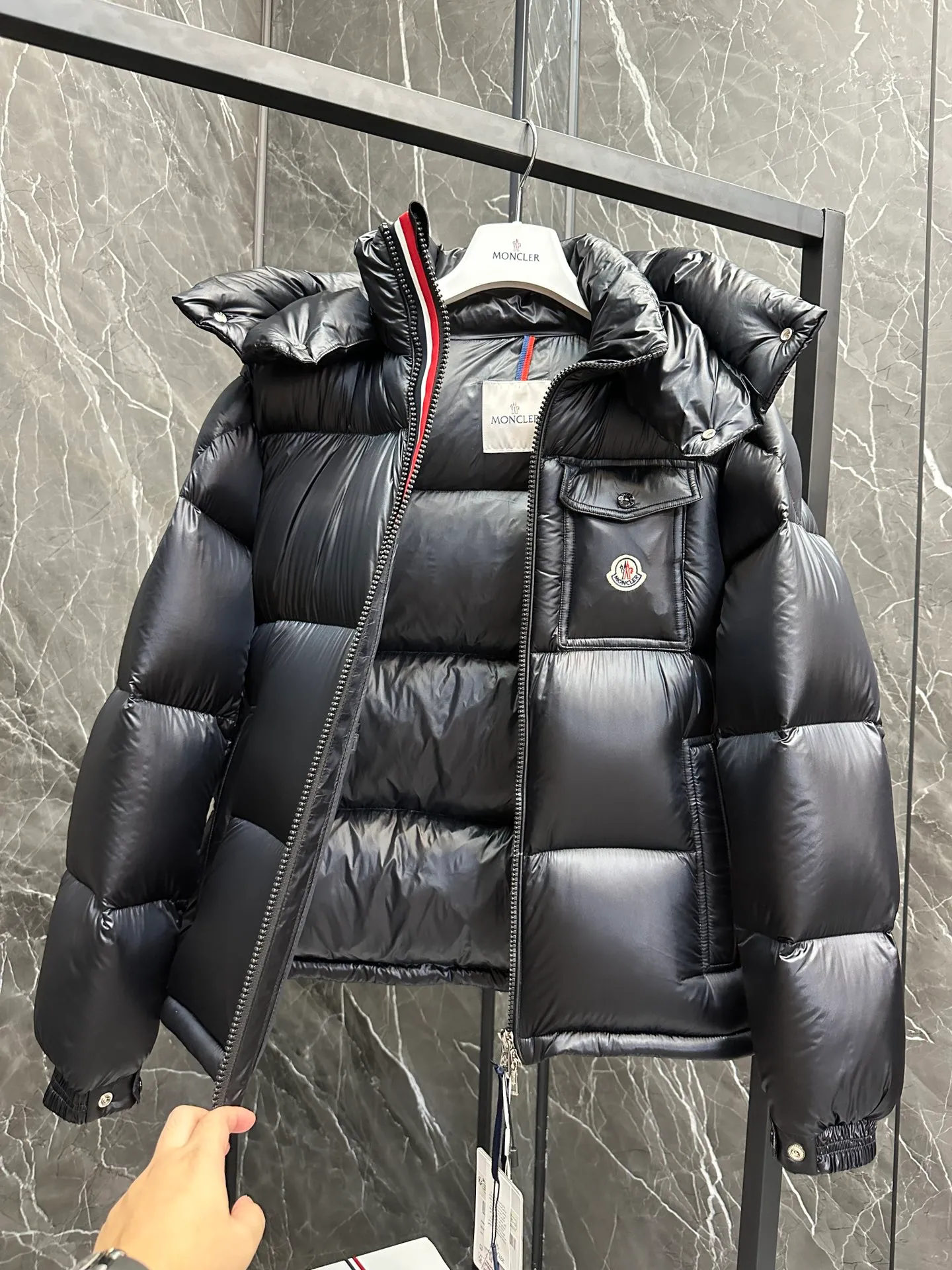 P740 ⬆️Moncler Montbeliard Short Men's Down Jacket Jacket Montbeliard Men's Short Down Jacket has warmth and protection functions, highlighting the fashionable Moncler aesthetic, and is a popular product. The Montbeliard down jacket is made from shiny patented nylon and features recognizable rectangular quilting. Featuring a hooded design and signature patch pocket at chest. Details •Made from nylon laqué fabric •Nylon laqué lining •Filled with down •Removable and adjustable hood with drawstring closure •Internal flap with webbing •Black pocket detail at lower end •Zipper closure •Snap-button closure at collar •Zipper pockets •Push-button closure at patch pockets •Adjustable cuffs •Adjustable elastic drawstring hem Size: 1-5 Couple's Black D9875067650
