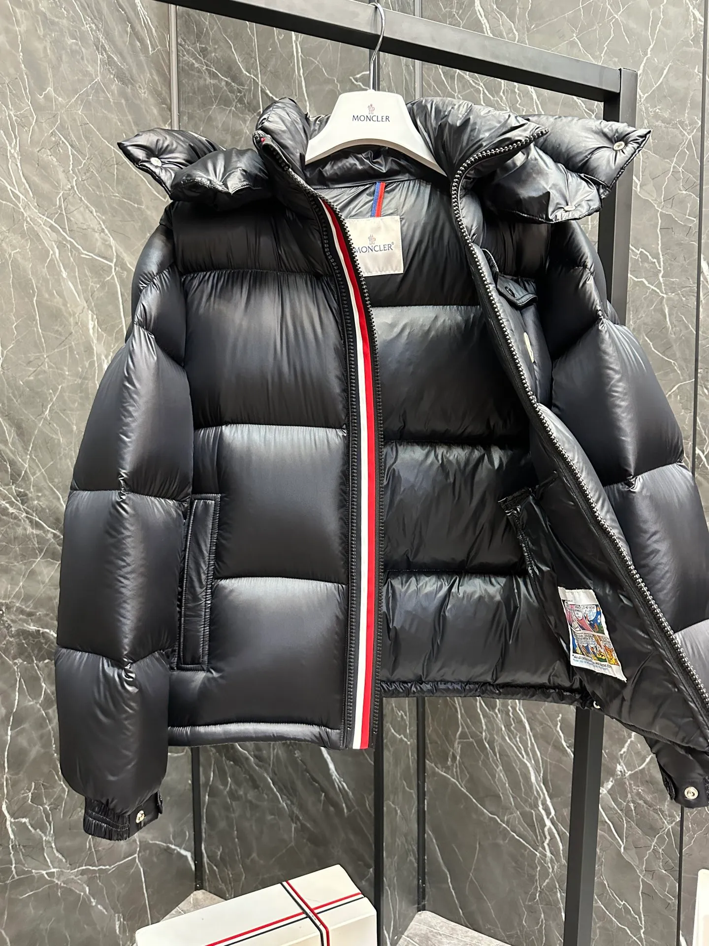 P740 ⬆️Moncler Montbeliard Short Men's Down Jacket Jacket Montbeliard Men's Short Down Jacket has warmth and protection functions, highlighting the fashionable Moncler aesthetic, and is a popular product. The Montbeliard down jacket is made from shiny patented nylon and features recognizable rectangular quilting. Featuring a hooded design and signature patch pocket at chest. Details •Made from nylon laqué fabric •Nylon laqué lining •Filled with down •Removable and adjustable hood with drawstring closure •Internal flap with webbing •Black pocket detail at lower end •Zipper closure •Snap-button closure at collar •Zipper pockets •Push-button closure at patch pockets •Adjustable cuffs •Adjustable elastic drawstring hem Size: 1-5 Couple's Black D9875067650