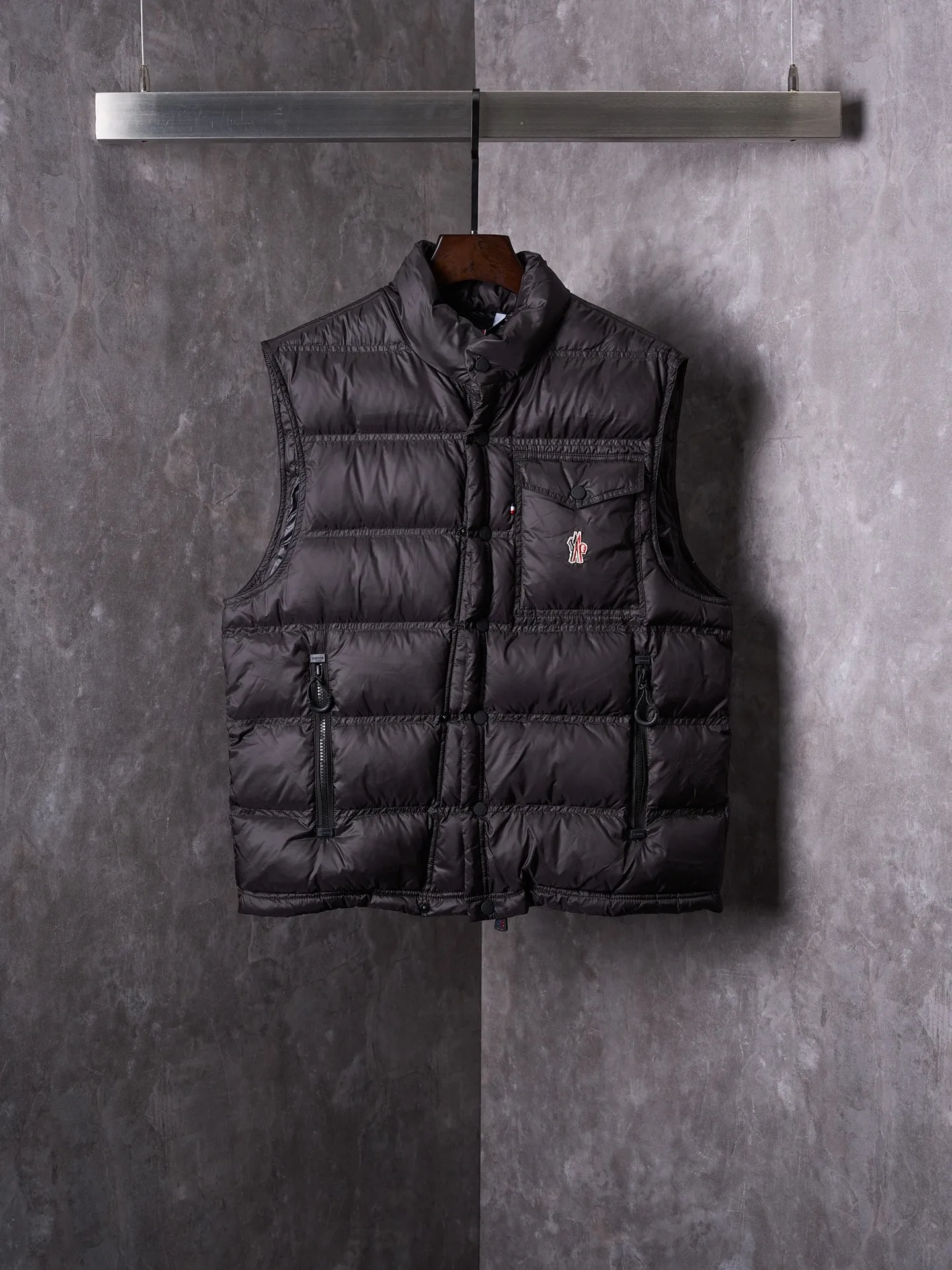 P680 Actual hanging auction] MONCLER/Mandow embroidered reflective logo stand-up collar down vest [Ready stock] 1 2 3 4 It is made of extremely fine nylon yarn and woven in a high-density way. The number of yarns per unit area is large, and the gaps between the yarns are very small, which can effectively block the penetration of cold wind. The fine weave keeps it lightweight and soft to the touch, physically restricting the lightweight down fibers from slipping through the gaps. Nylon fiber itself has good wear resistance and is not easy to snag, which significantly extends its service life and can easily cope with the needs of multiple scenarios.  The lining is made of high-density weaving of 100% polyester fiber, with a thickness of 0.08mm to avoid increasing the overall weight and making it smooth to wear. The high-density weaving structure forms a wind resistance layer to protect the thermal efficiency of the thermal layer from loss. It can withstand the expansion pressure of down and prevent deformation and damage after long-term use.  It uses 90 white duck down with a weight of 130g to ensure excellent thermal insulation performance. After strict screening and processing, the velvet is not easy to get drilled, ensuring durability.  Through the reflective cloth punching process, the logo is regularly arranged on the triangular reflective mark with dozens of small holes, which not only improves functionality but also enhances recognition and aesthetics.