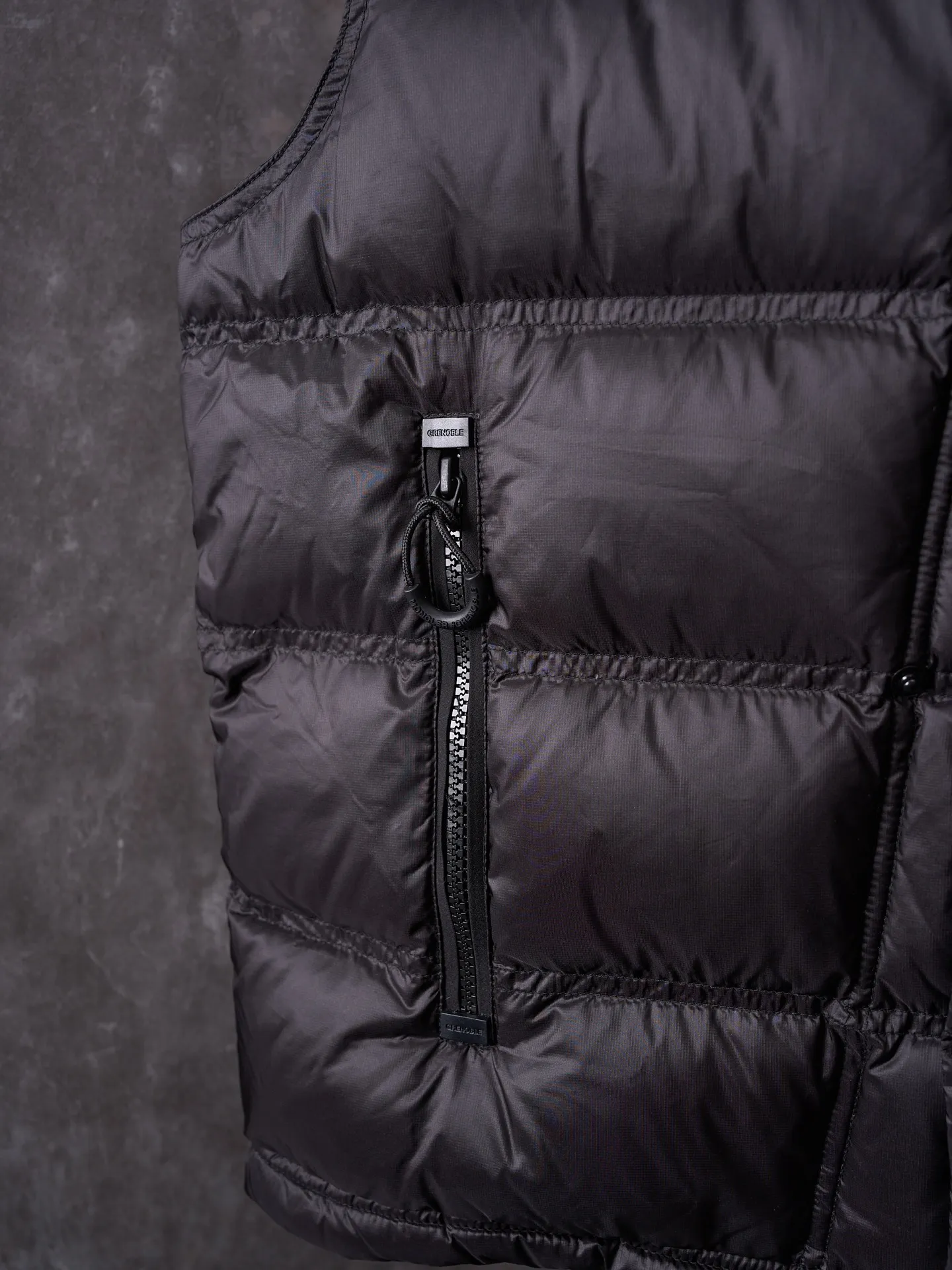 P680 Actual hanging auction] MONCLER/Mandow embroidered reflective logo stand-up collar down vest [Ready stock] 1 2 3 4 It is made of extremely fine nylon yarn and woven in a high-density way. The number of yarns per unit area is large, and the gaps between the yarns are very small, which can effectively block the penetration of cold wind. The fine weave keeps it lightweight and soft to the touch, physically restricting the lightweight down fibers from slipping through the gaps. Nylon fiber itself has good wear resistance and is not easy to snag, which significantly extends its service life and can easily cope with the needs of multiple scenarios.  The lining is made of high-density weaving of 100% polyester fiber, with a thickness of 0.08mm to avoid increasing the overall weight and making it smooth to wear. The high-density weaving structure forms a wind resistance layer to protect the thermal efficiency of the thermal layer from loss. It can withstand the expansion pressure of down and prevent deformation and damage after long-term use.  It uses 90 white duck down with a weight of 130g to ensure excellent thermal insulation performance. After strict screening and processing, the velvet is not easy to get drilled, ensuring durability.  Through the reflective cloth punching process, the logo is regularly arranged on the triangular reflective mark with dozens of small holes, which not only improves functionality but also enhances recognition and aesthetics.