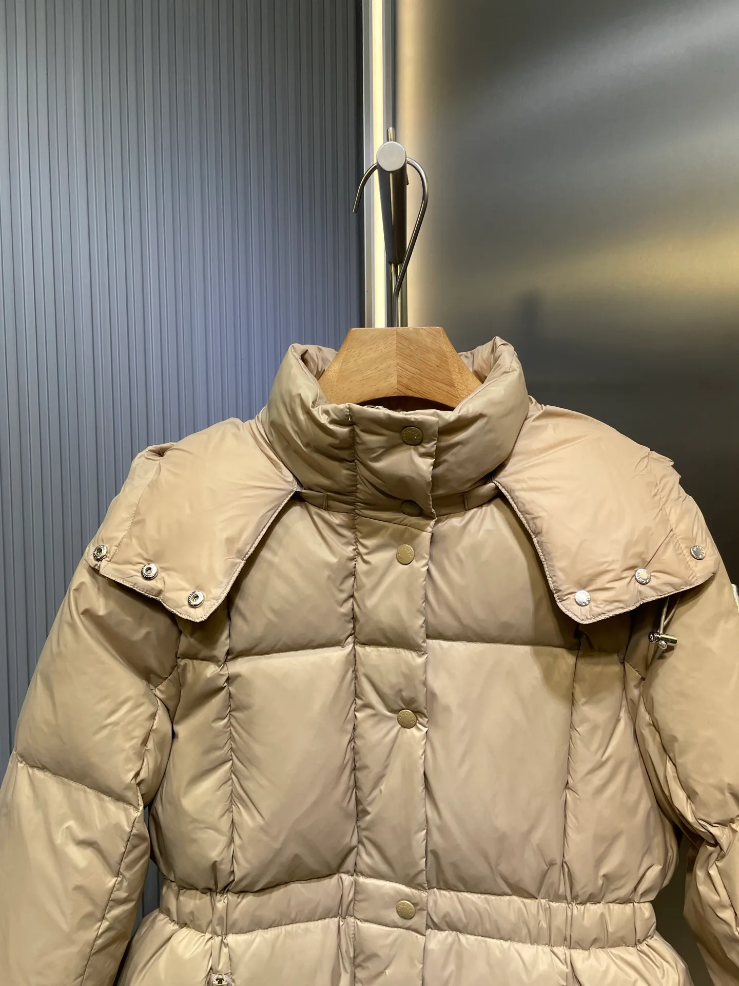 P910 MONCLER 25FW new autumn and winter product. Waisted black gold Agneux women's square quilted hooded short down jacket. The Agneux down jacket combines protective fabrics and exquisite textures. Short fit in functional nylon with a glossy satin finish. Paired with a nipped-in waist design, it outlines a feminine silhouette. Made of nylon Longue saison lining Filled with down Detachable and adjustable hood Zip and snap fastening Zippered pockets Elastic waist Black Apricot Sizes S M L