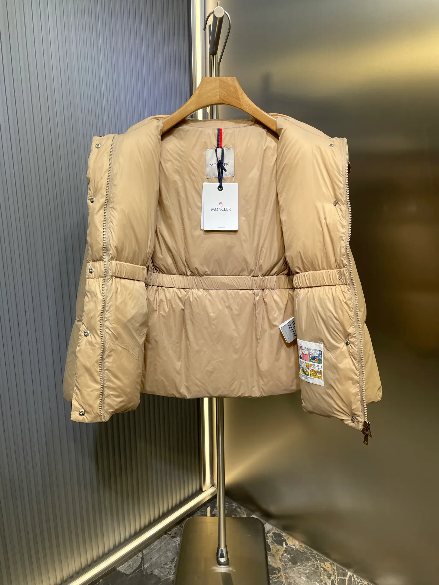 P910 MONCLER 25FW new autumn and winter product. Waisted black gold Agneux women's square quilted hooded short down jacket. The Agneux down jacket combines protective fabrics and exquisite textures. Short fit in functional nylon with a glossy satin finish. Paired with a nipped-in waist design, it outlines a feminine silhouette. Made of nylon Longue saison lining Filled with down Detachable and adjustable hood Zip and snap fastening Zippered pockets Elastic waist Black Apricot Sizes S M L