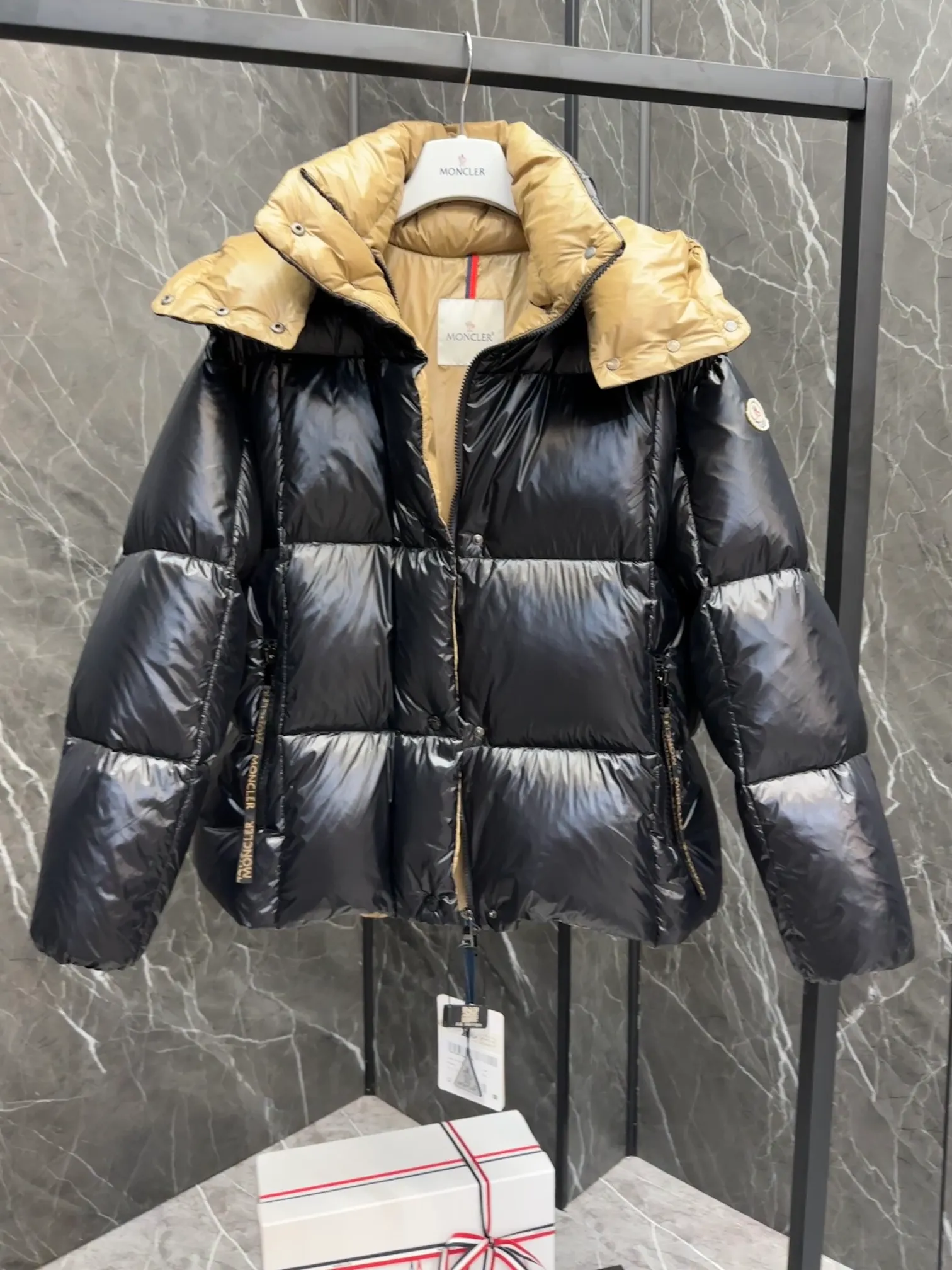 P720 Premium Down ⬆️ The Moncler Parana down jacket stands out with its shiny patented nylon fabric, featuring contrasting interior and exterior tones. The short design, the hood is detachable when the weather warms up, and the large drawstring draw inspiration from trendy brand logo fashion, embellished with Moncler letters.  •Made of patented nylon •Patented nylon lining •95 EU goose down filling •Removable hood •Contrast color lining •Zip and snap fastening •Zip pockets •Felt logo Size:0-3 Women's D9880046730