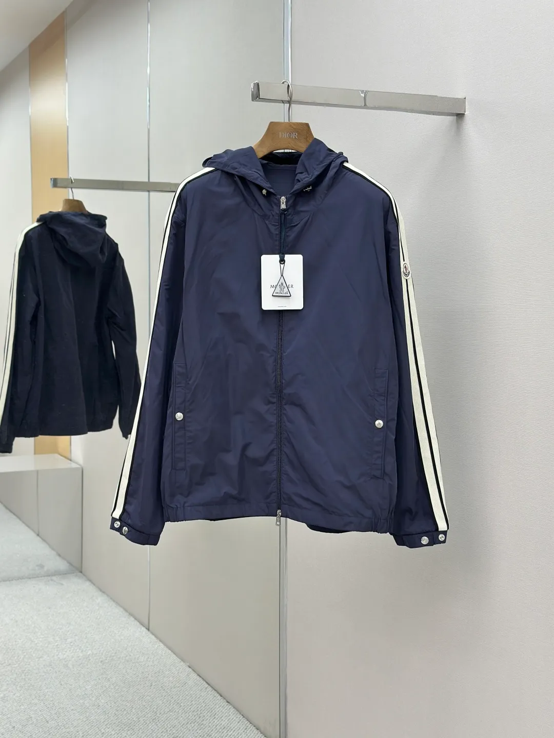 P560 MONCLER web-trimmed lightweight jacket Fabric selection: 100% polyester fiber is used to create a tough protective outer layer. It is known for its excellent tear resistance and wear resistance. It can quickly return to flatness during wearing and maintain the crisp and stylish appearance of the clothing for a long time. At the same time, it is not easy to deform after being washed for a long time.   Features: Two different colored decorative strips added to the center part of the sleeves. This design element can not only add visual highlights to clothing, making it more fashionable and unique. Craftsmanship: The webbing is precisely positioned along the cuffs to the seam of the collar and hat to ensure symmetry and overall smoothness. Before actual sewing, use very fine basting stitches for pre-fixing. This step is crucial to prevent the webbing from slipping, twisting, or wrinkling during sewing and ensuring that the final stitch is straight and perfect.  Accessories: Custom zipper puller, custom buttons with logo, custom hood drawstring elastic buckle SIZE: 1 2 3 4