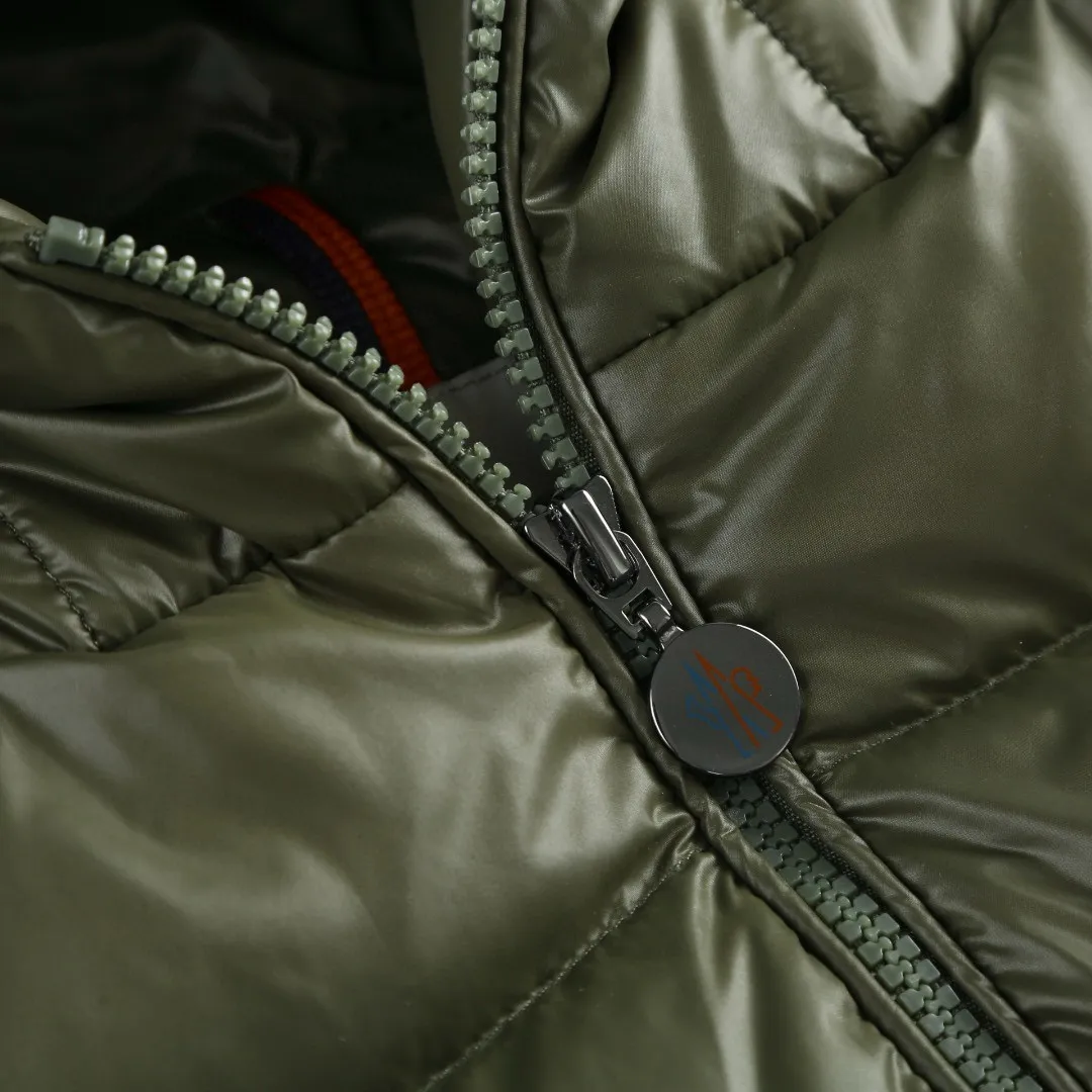 P910 [Exclusive supply] Moncler hooded brim quilted embroidered down jacket (green). The high-quality filling is made of 90 selected white duck down, with a weight of 210g, ensuring fast fluffy rebound, lightness and warmth. The fabric is made of longue saison fabric made of high-count polyamide fiber, which is famous for its excellent tensile strength and lightness. Its good flexibility makes the fabric less prone to wrinkles and keeps it crisp and stylish for a long time. The tight weave effectively blocks the invasion of cold wind and locks in the warm air generated by the down layer. The high-density nylon surface forms a certain lotus leaf effect, making it difficult for small water droplets to penetrate, keeping the interior dry and effectively extending the service life of the down. The lining is made of ultra-fine denier woven high-density lining, with a thickness of 0.08mm to avoid increasing the overall weight and making it smooth to wear. The high-density woven structure forms a wind resistance layer to protect the thermal efficiency of the thermal layer from loss. It can also withstand the expansion pressure of down and prevent deformation and damage after long-term use. The quilted letter logo on the brim uses contour quilting technology. The stitches are routed along the edge of the set outline, and the filler is compressed inside the letter graphic, so that the logo is three-dimensional and the pattern is clear. Size:1-2-3-3
