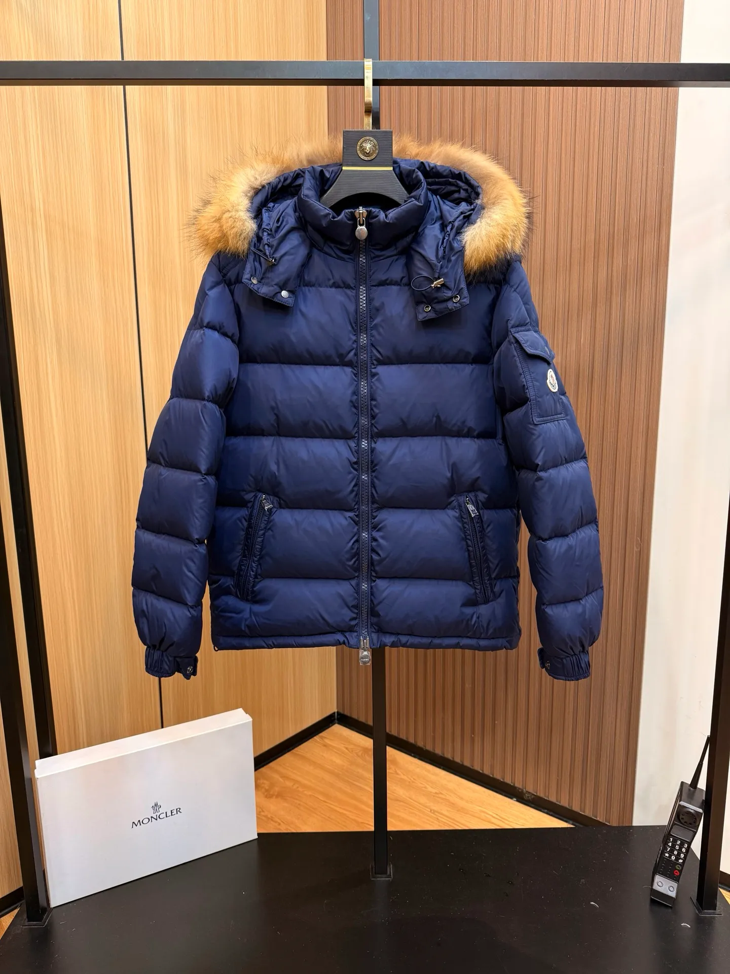 P1040 Moncler Mayaf short men's down jacket. The hood is removable. The fur collar is removable. Based on Maya, a removable fur collar is added. The Mayaf men's hooded down jacket is made of functional nylon fabric, and the hood is equipped with removable synthetic material trim.  The Mayaf short down jacket is a reinterpretation of the classic Moncler Maya style in an instantly recognizable silhouette, with a removable hood and adjustable hem. Made from functional fabric with removable synthetic trim on the hood. The sleeves are embellished with classic patch pockets, reflecting the brand's signature style. Details •Made from functional fabric •Technical fabric lining •Down-filled •Push-stud collar •Detachable hood with removable synthetic trim •Zip closure •Zip pockets •Patch pockets with press-stud •Adjustable elastic cuffs •Adjustable drawstring hem