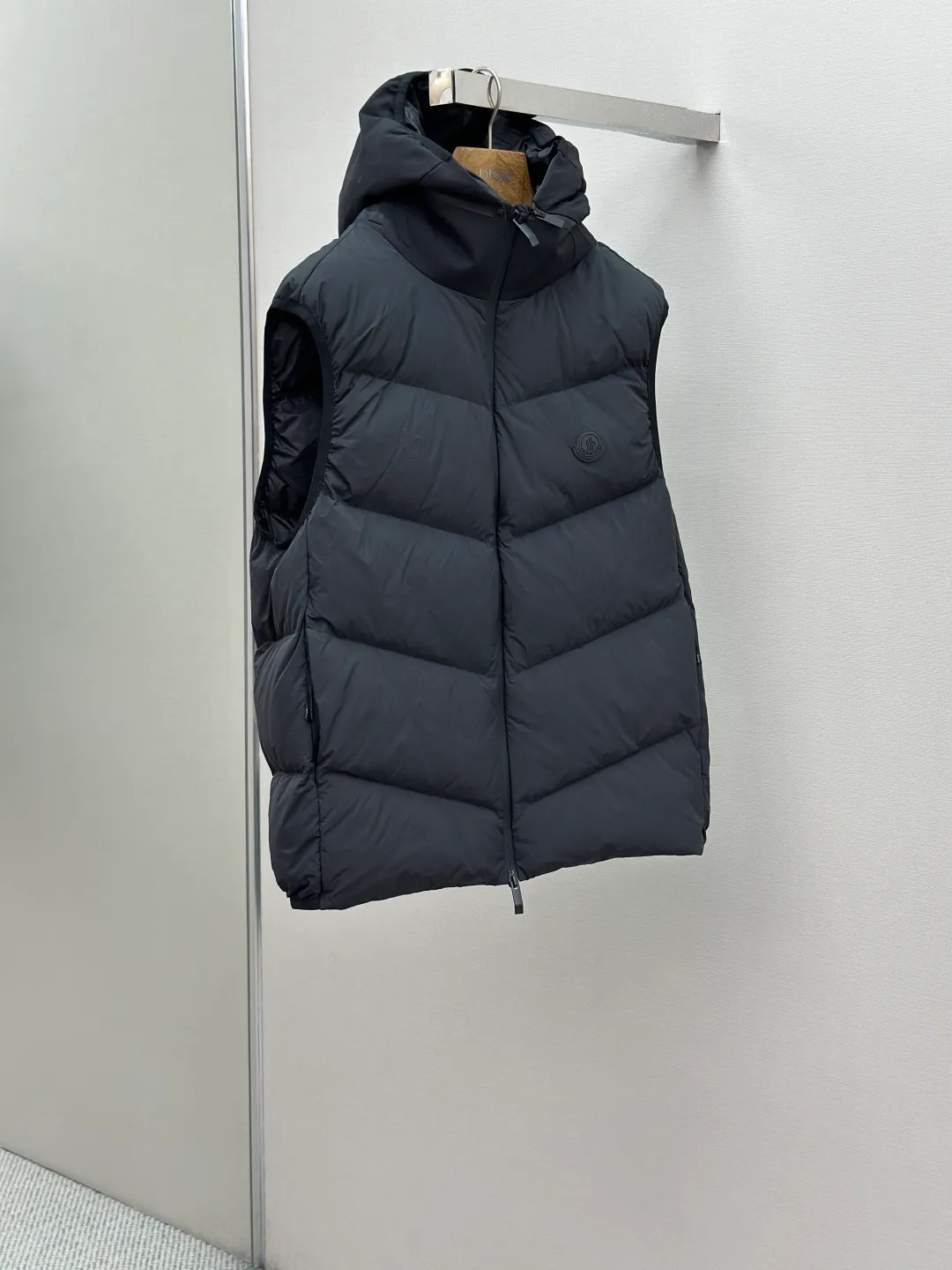 P660 MONCLER Badge Hooded Down Vest Fabric selection: Made of nylon fabric made of 100% nylon, which is woven into a tight and tough fabric through advanced textile technology. It improves the strength of the skeleton to effectively block the invasion of cold wind and lock the warm air generated by the down layer. After tight weaving and special treatment, it has waterproof and windproof functions. The surface forms a certain lotus leaf effect, and is wrinkle-resistant and not easily deformed, making it easy for daily care.  Technology: The quilting stitches are sewn in a diagonal direction at an angle of approximately 70 degrees. The diagonal lines are arranged in parallel. The fabric and filling are planned into different functional areas, and the quilting stitches in each partition are relatively independent. This allows the finished product to produce a larger deformation space along the diagonal direction when stretched and pressed, making it less likely to tighten and break, and has rich visual effects, modern and advanced features.  Details: After the hood is removed, the stand-up collar displays an embossed logo of the same color, adding a unique visual experience and tactile details.  High-quality filling: It is filled with 90% selected white duck down, weighing 170g, ensuring fluffy rebound, lightness and warmth.  Accessories: One-to-one customized zipper pendant, one-to-one customized badge, one-to-one customized three-label SIZE: 1 2 3 4