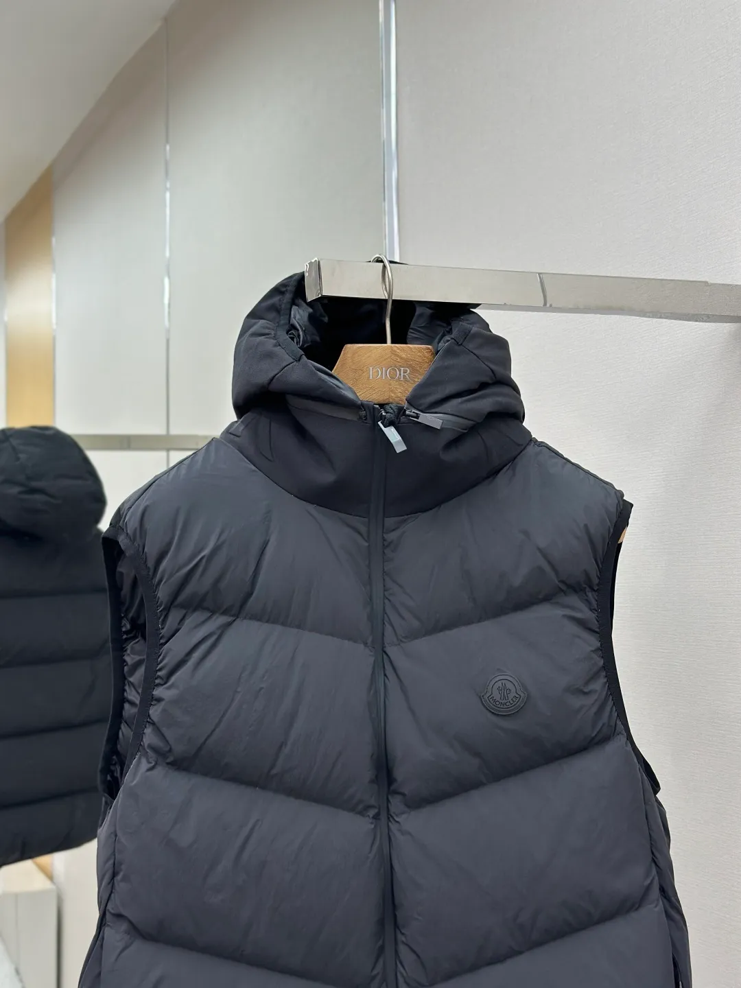 P660 MONCLER Badge Hooded Down Vest Fabric selection: Made of nylon fabric made of 100% nylon, which is woven into a tight and tough fabric through advanced textile technology. It improves the strength of the skeleton to effectively block the invasion of cold wind and lock the warm air generated by the down layer. After tight weaving and special treatment, it has waterproof and windproof functions. The surface forms a certain lotus leaf effect, and is wrinkle-resistant and not easily deformed, making it easy for daily care.  Technology: The quilting stitches are sewn in a diagonal direction at an angle of approximately 70 degrees. The diagonal lines are arranged in parallel. The fabric and filling are planned into different functional areas, and the quilting stitches in each partition are relatively independent. This allows the finished product to produce a larger deformation space along the diagonal direction when stretched and pressed, making it less likely to tighten and break, and has rich visual effects, modern and advanced features.  Details: After the hood is removed, the stand-up collar displays an embossed logo of the same color, adding a unique visual experience and tactile details.  High-quality filling: It is filled with 90% selected white duck down, weighing 170g, ensuring fluffy rebound, lightness and warmth.  Accessories: One-to-one customized zipper pendant, one-to-one customized badge, one-to-one customized three-label SIZE: 1 2 3 4