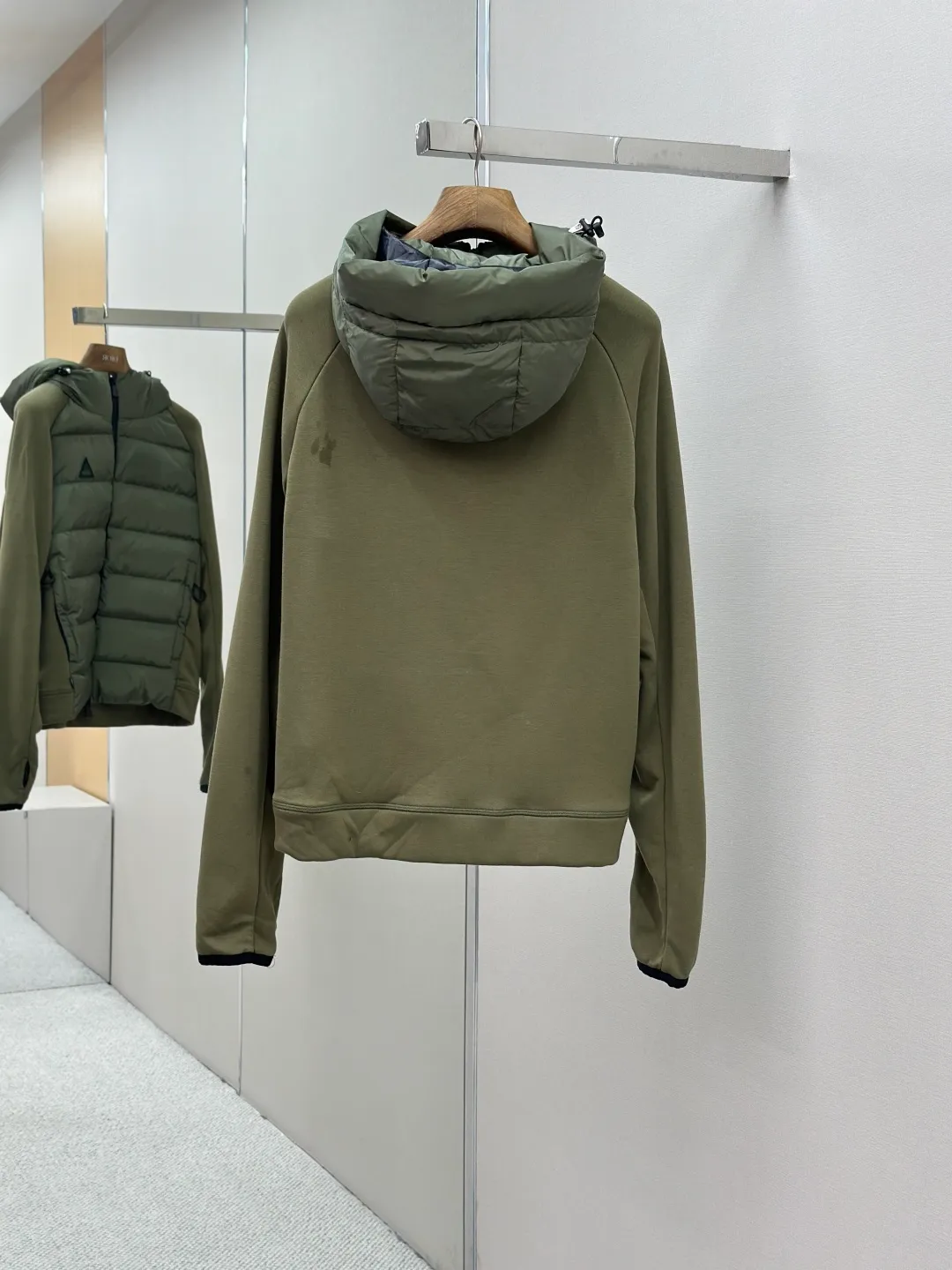 P810 Moncler logo woven splicing down jacket, customized matte crystal lattice air shield velvet and 300D high-density calendered coating, using the new national standard 90 white duck down (welcome to test), full of down, full of warmth, light and fluffy, with the dark green of the overlapping mountains as the background color, all things accumulating, creating its own scenery in silence The Monlcer triangle logo is embellished on the chest, the power aesthetics of the minimalist logo The concentrated down filling in the front area creates dynamic insulation for the core heat dissipation zone of the human body. The hooded down is a moving warm flow barrier for the head and neck, forming a thermal energy circulation system with the front area. The elastic woven sleeves provide freedom of movement with a sense of compression, forming a relaxed and warm philosophy. The real high-end is to let function become the footnote of style. Process 1: Computer mechanical down filling. Prioritize the liner pattern by making a pattern to determine the down filling area and determine the weight of down per square meter according to the original three-dimensional effect. Thus, the amount of down filling for each cut piece is calculated. The computer down filling machine uses a digital weighing unit to achieve stable measurement. Process 2: 3D three-dimensional quilting technology. With the programming system of the CNC quilting machine, the down in different areas is accurately separated to ensure that the filling is evenly fixed after sewing and avoid agglomeration or displacement. Process 3: Computer template machine line running process. The computer template machine line line process shows extremely high neatness and smoothness. The craftsman's precise control of the size during the operation ensures that each line meets the design requirements. The lines of the entire template are smooth and unified, neat and beautiful. Process 4: Triple locking five-thread dense stitching process. Main seam locking + diagonal reinforcement + raw edge wrapping. Triple structure. Forming a three-dimensional protective net at the edge of the fabric to avoid stitch breakage. Paving materials: Customized Moncler zippers. Customized Moncler rope loops. Customized Moncler logo. Customized Moncler eyelets. Customized Moncler trademark. Size: S M L XL