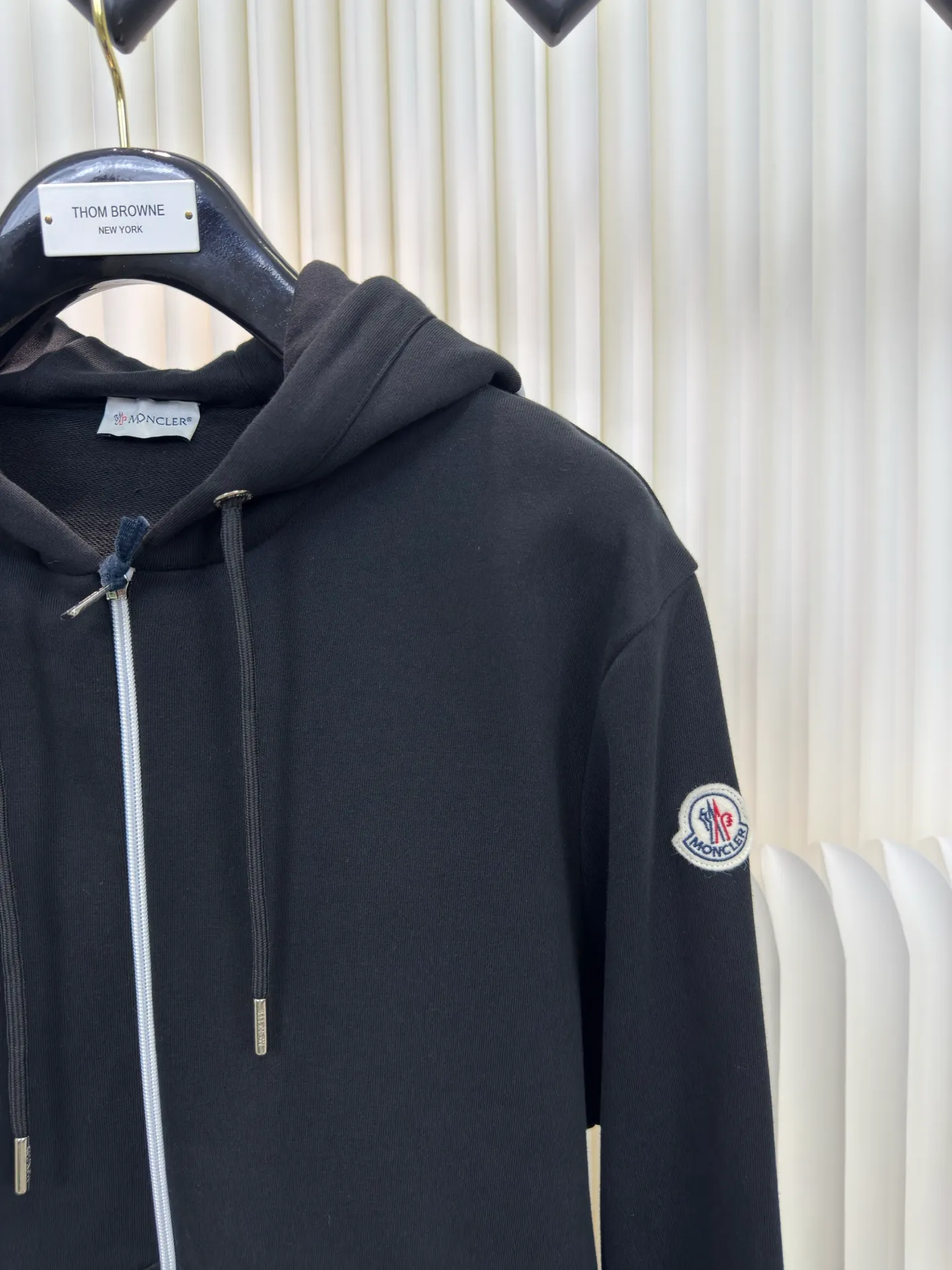 P500 MONCLER printed logo hooded sweatshirt is made of lightweight turned-over velvet cotton fabric. High-density cotton fiber is used to achieve internal and external differentiation in a single layer of fabric. The outer plain weave is tight and wear-resistant, and the inner layer is sanded to form a short dense suede surface. The dense plain weave structure resists wind and splashes, the brushed suede surface is skin-friendly, and the short pile has been treated to eliminate static electricity to avoid sticking to the skin. A very small amount of grooved polyester moisture-conducting yarn is embedded in the cotton fiber, which quickly directs sweat from the inner suede surface to the outer layer for evaporation through the capillary effect, solving the problem that the inside-out suede is prone to stuffiness. By actively intervening in the shrinkage potential of the cotton fiber, the fabric is achieved from being volatile to stable, improving dimensional stability, and at the same time not prone to deformation and wrinkles.   A high-saturation pattern is displayed on the center of the cap through glue printing. The scraper pressure is even and the scraping is performed in 5 steps to ensure that the glue is fully penetrated and covered. After curing at high temperature, the pigment is firmly combined with the cotton fiber. The ink absorption and penetration characteristics of the cotton fiber make the pattern less likely to fall off due to friction. Size S M L XL