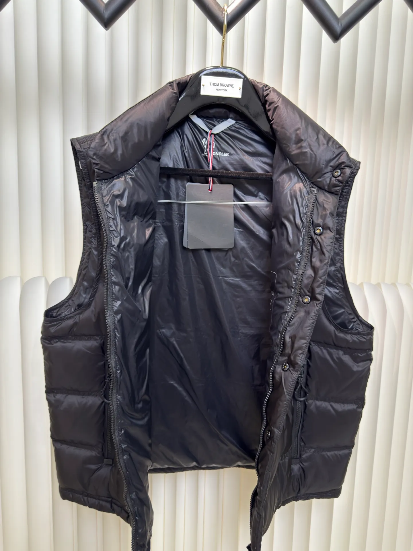 P700 MONCLER masked down vest with reflective markings is made of 90 white duck down with a weight of 130g to ensure excellent thermal insulation performance. After strict screening and processing, the velvet is not easy to get drilled, ensuring durability.  It is made of extremely fine nylon yarn and is woven in a high-density manner. The number of yarns per unit area is large, and the gaps between the yarns are very small, which can effectively block the penetration of cold wind. The fine weave keeps it lightweight and soft to the touch, physically restricting the lightweight down fibers from slipping through the gaps. Nylon fiber itself has good wear resistance and is not easy to snag, which significantly extends its service life and can easily cope with the needs of multiple scenarios.  The lining is made of high-density weaving of 100% polyester fiber, with a thickness of 0.08mm to avoid increasing the overall weight and making it smooth to wear. The high-density weaving structure forms a wind resistance layer to protect the thermal efficiency of the thermal layer from loss. It can withstand the expansion pressure of down and prevent deformation and damage after long-term use.  Through the reflective cloth punching process, the logo is regularly arranged on the triangular reflective mark with dozens of small holes, which not only improves functionality but also enhances recognition and aesthetics. Size 1 2 3 4
