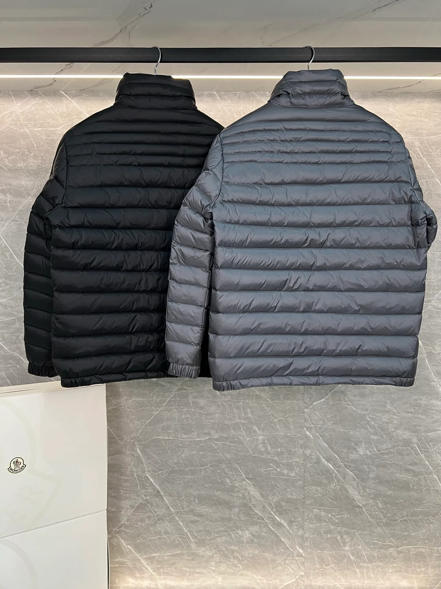 P780 Moncler Arnique short and lightweight men's down jacket. Super soft and delicate fabric, white duck down filling. Extremely lightweight and warm. The Arnique hooded down jacket is made of polyester fiber outer fabric and is Moncler's classic men's design item.  The Arnique short down jacket features classic checkered quilting and signature patch pockets on the sleeves, highlighting the Moncler style. The outer fabric reflects the brand's commitment to lowering its environmental footprint. Modular design, removable hood can be easily put on and taken off according to weather conditions. Details Made of polyester outer fabric Polyester lining Filled with down Size: 1-5 Silver Gray Black