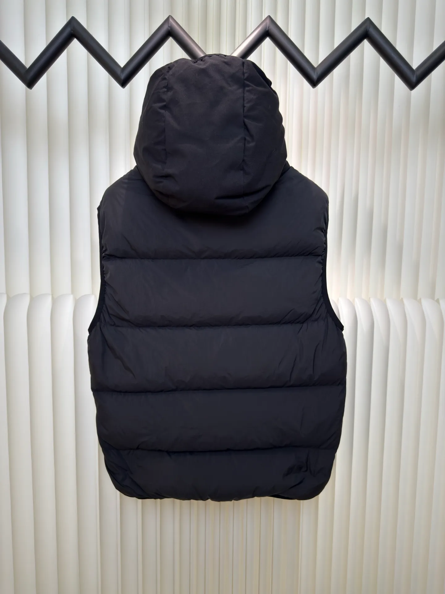 P660 MONCLER Badge Hooded Down Vest is made of nylon fabric made of 100% nylon. It is woven into a tight and tough fabric through advanced textile technology. It improves the strength of the frame and effectively blocks the invasion of cold wind and locks in the warm air generated by the down layer. After tight weaving and special treatment, it is waterproof and windproof. The surface forms a certain lotus leaf effect. It is also wrinkle-resistant and not easy to deform, making it easy for daily care.  The quilting stitches are sewn in a diagonal direction at an angle of about 70 degrees, and the diagonal lines are arranged in parallel. The fabric and filling are planned into different functional areas, and the quilting stitches in each partition are relatively independent. This allows the finished product to produce a larger deformation space along the diagonal direction when stretched and pressed, making it less likely to tighten and break, and has rich visual effects, modern and advanced features.  After the hood is removed, the stand-up collar displays an embossed logo of the same color, adding a unique visual experience and tactile details. High-quality filling: It is filled with 90% selected white duck down, weighing 170g, ensuring fluffy rebound, lightness and warmth. Size 1 2 3 4