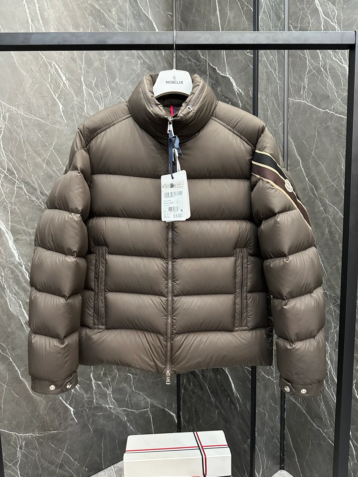 P920 2024N haute couture down moncler solayan men's three-color trimmed short down. Premium goose down filling. The most delicate, lightest and neatest fabric. Solayan men's short down is decorated with seasonal iconic stripe details, blending sportsmanship and timeless style. Solayan down is made of micro chic fabric and has a tough square shape design, highlighting Moncler's sporty spirit. This cropped style has tricolor stripes on the sleeves, a seasonal take on the brand's signature. Comes with a practical pull-out hood. Details · Made of micro chic nylon fabric · Micro chic nylon lining · Filled down · Pull-out hood · Zipper closure · Zipper pocket · Adjustable cuffs · Elastic drawstring hem · Tri-color trim on sleeves size: 1-5 Color: white, dark brown, black