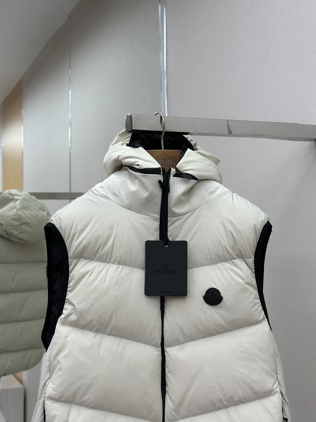 P660 MONCLER Badge Hooded Down Vest Fabric selection: Made of nylon fabric made of 100% nylon, which is woven into a tight and tough fabric through advanced textile technology. It improves the strength of the skeleton to effectively block the invasion of cold wind and lock the warm air generated by the down layer. After tight weaving and special treatment, it has waterproof and windproof functions. The surface forms a certain lotus leaf effect, and is wrinkle-resistant and not easily deformed, making it easy for daily care.  Technology: The quilting stitches are sewn in a diagonal direction at an angle of approximately 70 degrees. The diagonal lines are arranged in parallel. The fabric and filling are planned into different functional areas, and the quilting stitches in each partition are relatively independent. This allows the finished product to produce a larger deformation space along the diagonal direction when stretched and pressed, making it less likely to tighten and break, and has rich visual effects, modern and advanced features.  Details: After the hood is removed, the stand-up collar displays an embossed logo of the same color, adding a unique visual experience and tactile details.  High-quality filling: It is filled with 90% selected white duck down, weighing 170g, ensuring fluffy rebound, lightness and warmth.  Accessories: One-to-one customized zipper pendant, one-to-one customized badge, one-to-one customized three-label SIZE: 1 2 3 4
