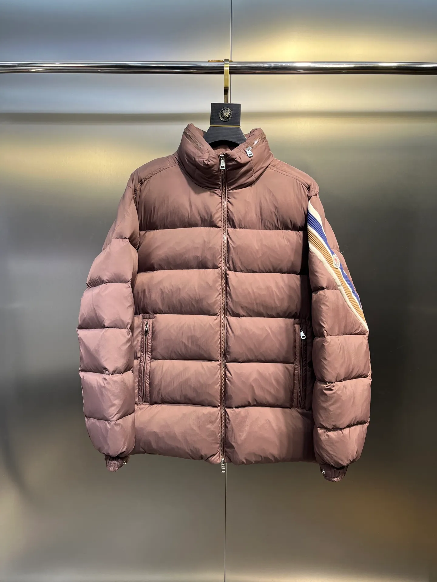 P840 Moncler Solayan men's tri-color trim short down jacket. Filled with premium goose down. The finest, lightest and neatest fabric. Solayan men's short down jacket is decorated with the season's signature stripe details, blending sporty spirit with timeless style. The Solayan down jacket is made of micro chic fabric and has a tough square shape design, highlighting Moncler's sporty spirit. This cropped down jacket features tricolor stripes on the sleeves, a seasonal take on the brand's signature. Comes with a practical pull-out hood. Details •Made from micro chic nylon fabric •Micro chic nylon lining •Down filled •Pull-out hood •Zip closure •Zip pockets •Adjustable cuffs •Elastic drawstring hem •Tri-color trim on sleeves Size: 1-5 Color: White Dark Brown Black