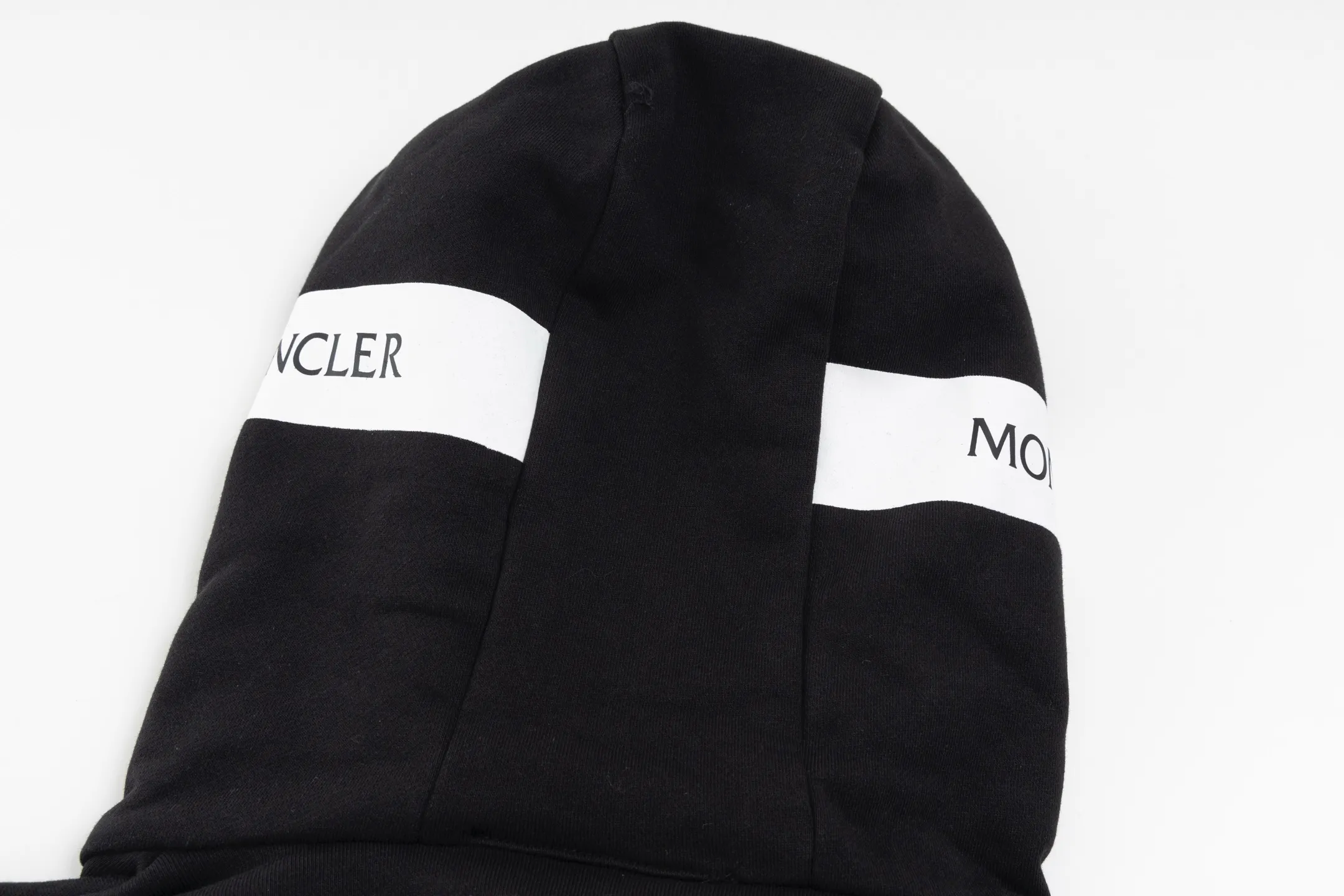 P480 Exclusive supply] Moncler slogan printed zipper hooded jacket is made of lightweight turned velvet cotton fabric. High-density cotton fiber is used to achieve internal and external differentiation in a single layer of fabric. The outer plain weave is tight and wear-resistant, and the inner layer is formed into a short dense suede surface through a sanding process. The dense plain weave structure resists wind and splashes, the brushed suede surface is skin-friendly, and the short pile has been treated to eliminate static electricity to avoid sticking to the skin. A very small amount of grooved polyester moisture-conducting yarn is embedded in the cotton fiber, which quickly guides sweat from the inner suede surface to the outer layer for evaporation through the capillary effect, solving the problem of the suede being easily stuffy. By actively interfering with the shrinkage potential of cotton fibers, the fabric is able to transition from changeable to stable, improving dimensional stability while being less prone to deformation and wrinkles. A high-saturation pattern is displayed on the center of the cap through glue printing. The scraper pressure is even and the scraping is performed in 5 steps to ensure that the glue is fully penetrated and covered. After curing at high temperature, the pigment is firmly bonded to the cotton fiber. The ink-absorbing and penetrating properties of the cotton fiber make the pattern less likely to fall off due to friction. Size:S/M/L/XL