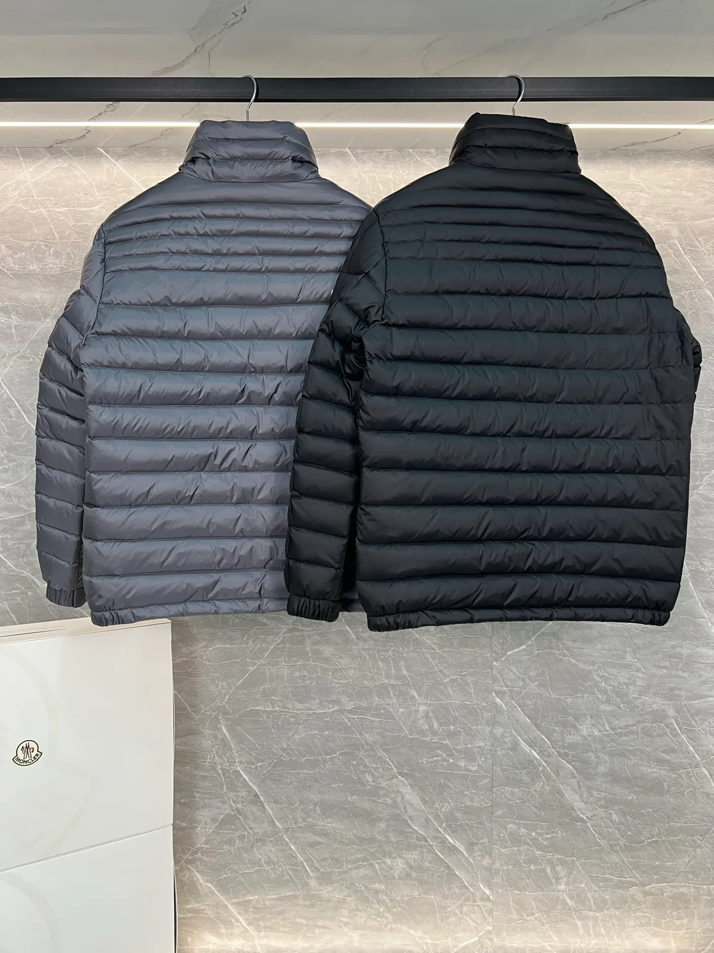 P780 Moncler Arnique short and lightweight men's down jacket. Super soft and delicate fabric, white duck down filling. Extremely lightweight and warm. The Arnique hooded down jacket is made of polyester fiber outer fabric and is Moncler's classic men's design item.  The Arnique short down jacket features classic checkered quilting and signature patch pockets on the sleeves, highlighting the Moncler style. The outer fabric reflects the brand's commitment to lowering its environmental footprint. Modular design, removable hood can be easily put on and taken off according to weather conditions. Details Made of polyester outer fabric Polyester lining Filled with down Size: 1-5 Silver Gray Black