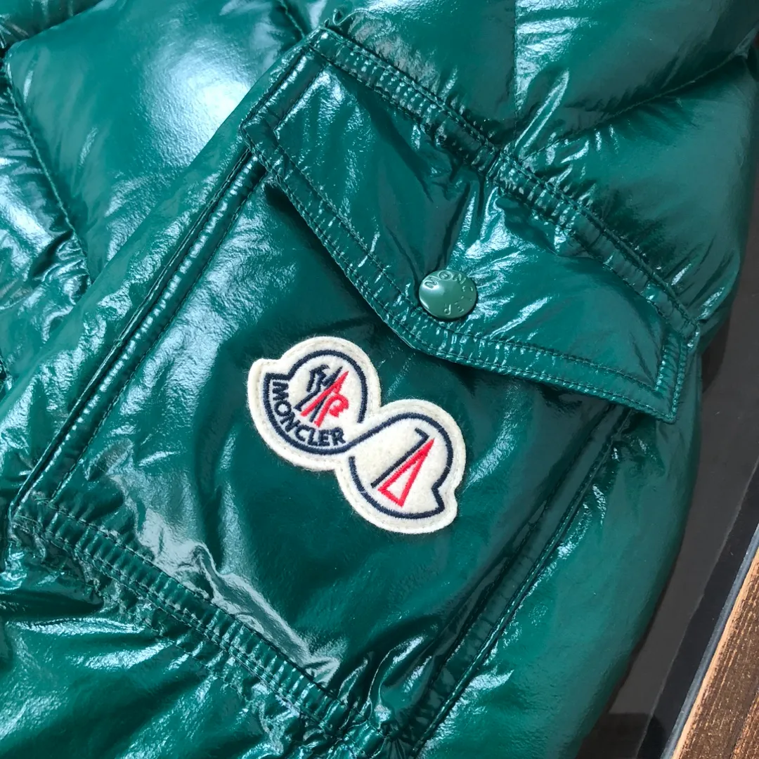 P800 Moncler Maya 70 Short Down Jacket Forest Green The iconic men's Moncler Maya 70 down jacket is highly recognizable and specially designed to celebrate the brand's 70th anniversary. The Moncler Maya down jacket has been reinterpreted specifically to celebrate Moncler's 70th anniversary, and the iconic silhouette has been refreshed in new colors. A classic example of the brand's DNA, it's made from shiny lacquered nylon and embellished with signature rectangular quilting. A classic, cropped design that spans seasons and fashions, the removable hood features a statement silhouette, removable hood and adjustable hem. The sleeves are decorated with the brand's signature classic patch pockets and a patchwork logo designed to celebrate the 70th anniversary. Color: black, ivory white, basalt gray, purple, cabin brown, forest green, code number: 1-2-3-4-5 (M～3xl)