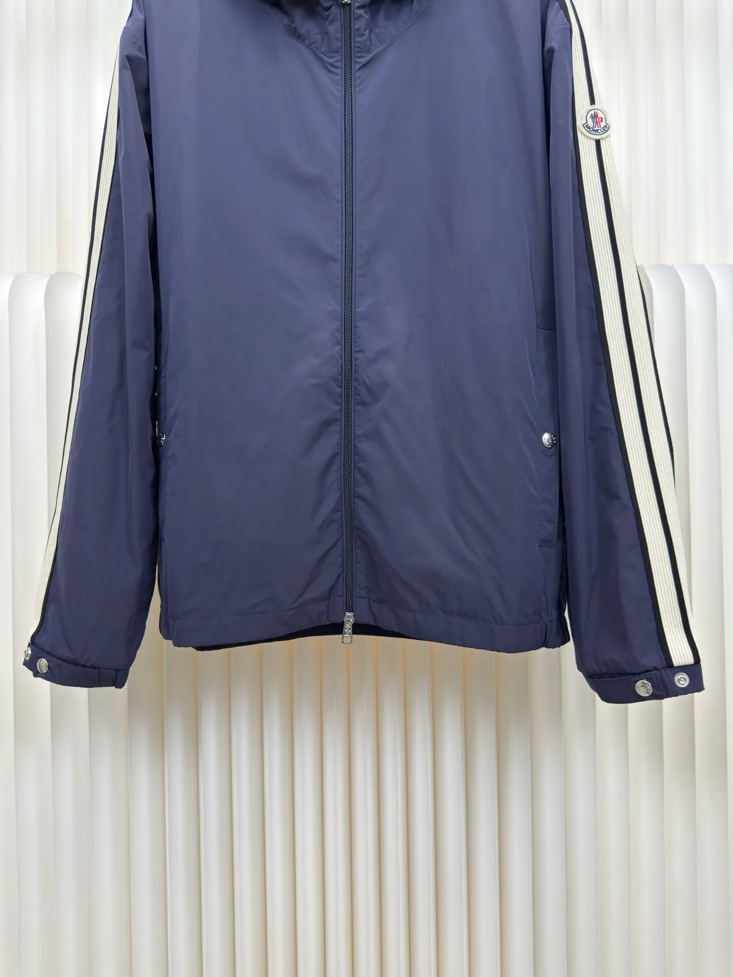 P570 MONCLER lightweight jacket with web trim at the mouth is made of 100% polyester fiber to create a tough protective outer layer. It is famous for its excellent tear resistance and wear resistance. It can quickly return to flatness during wearing and maintain the crisp and stylish appearance of the clothing for a long time. At the same time, it is not easy to deform after being washed for a long time.  Decorative edging in two different colors has been added to the center section of the sleeves. This design element not only adds visual highlights to clothing, making it more fashionable and unique. The webbing is precisely positioned along the cuffs to the seam of the collar and hat to ensure symmetry and overall smoothness. Before actual sewing, use very fine basting stitches for pre-fixing. This step is crucial to prevent the webbing from slipping, twisting, or wrinkling during sewing and ensuring that the final stitch is straight and perfect. Size 1 2 3 4