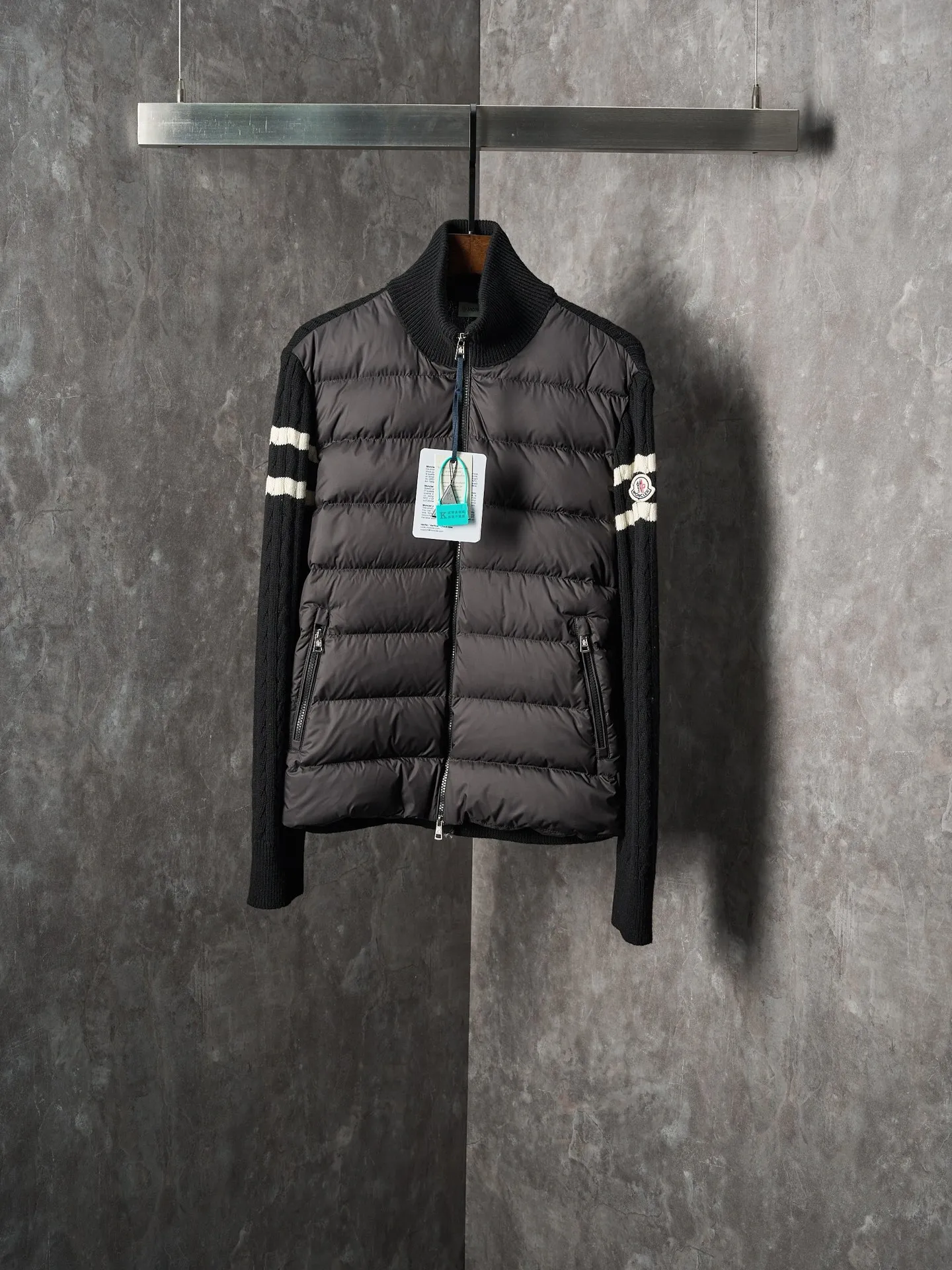P780 Actual auction] Moncler/Mask Black classic stand-up collar spliced ​​wool knitted parallel bars armband zipper down jacket [Ready stock] S/1 M/2 L/3 XL/4 The outer front fabric is made of 100% nylon (nylon). Its high-density structure achieves excellent windproof effect. It also has strong wear resistance and wrinkle resistance. It is scratch-free for daily wear and easy to take care of.  The splicing design of sweaters and down jackets not only retains the thermal performance of down jackets, but also incorporates the fashion elements of sweaters, making the overall garment both practical and fashionable.  High-quality material: filled with high-quality white duck down, with a filling capacity of 100g, which has excellent thermal insulation effect. At the same time, the sweater is made of wool, cashmere and other natural fibers, which are soft, comfortable and skin-friendly.  The sweaters and down jackets are carefully spliced ​​to ensure comfortable wearing and are not prone to threading or velvet loss.  High collar design: not only provides excellent thermal insulation effect, but also adds a unique sense of fashion, allowing the wearer to maintain style in the cold season.  Stripe decoration: The stripes on the sleeve arms are like bright brush strokes, embellished on the dark gray down jacket, injecting vitality and movement into the overall look, making the clothing more eye-catching.