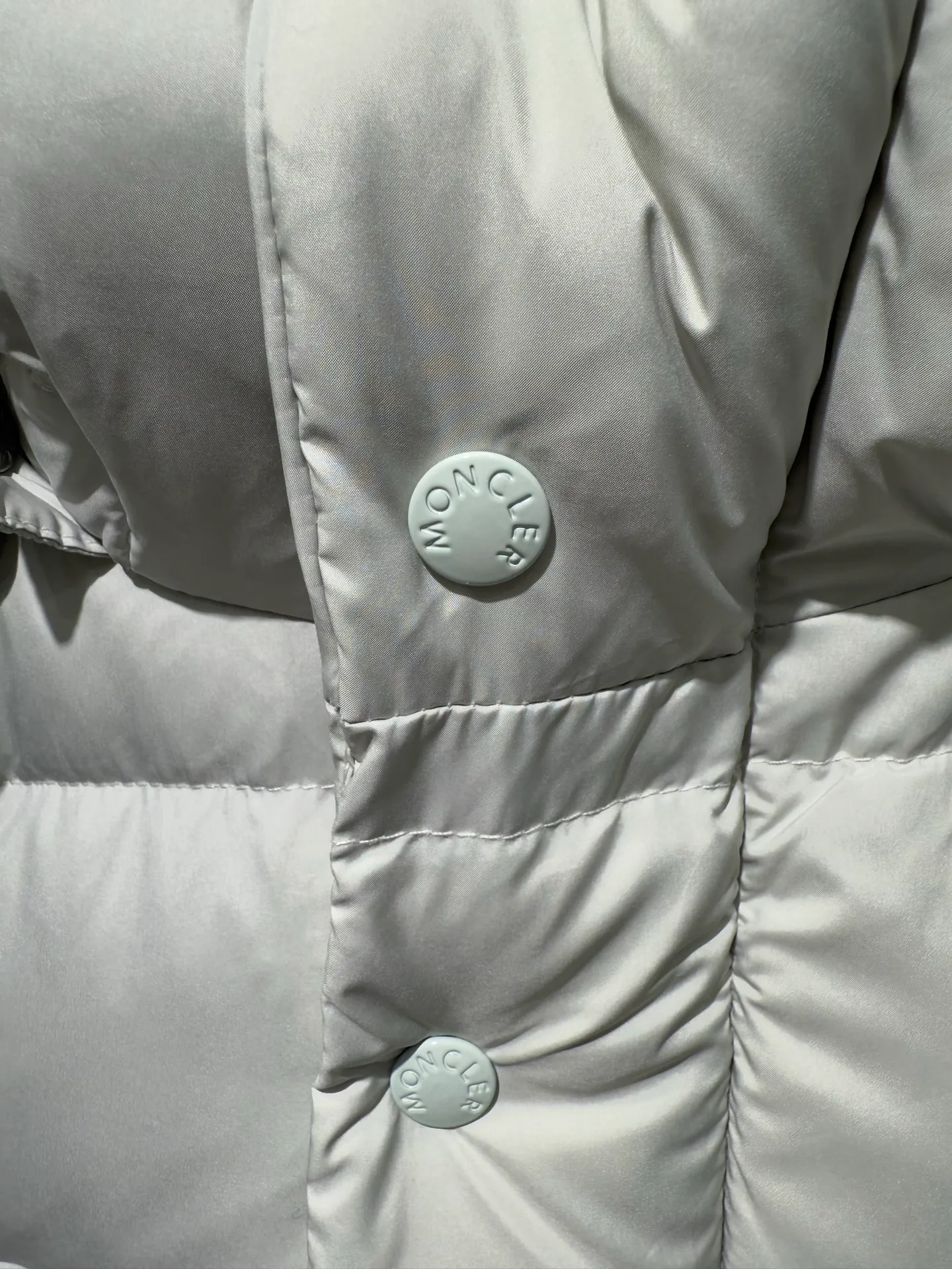 P1080 Moncler Maya Meng Maya Pearl Gray and White Short Down Jacket The Moncler Maya down jacket is made of matte nylon with iconic rectangular quilting, which is a model of Moncler style. A classic cropped design that transcends seasons and styles, it features a statement silhouette, removable hood and adjustable hem. The sleeves are embellished with classic patch pockets, showcasing the brand's signature style.  Fabric: 100% nylon, 90% white duck down Craftsmanship: Made of matte nylon, lacquered nylon lining filled with down, rectangular quilting, detachable hood with snap buttons that can be adjusted by drawstring, two-way zip fly, external and internal zipper pockets, adjustable elastic cuffs with snap buttons, hood with drawstring, sleeves with flap patch pockets, sleeves decorated with Moncler felt trademark. (Supports NFC function) Size: 01234 3543050