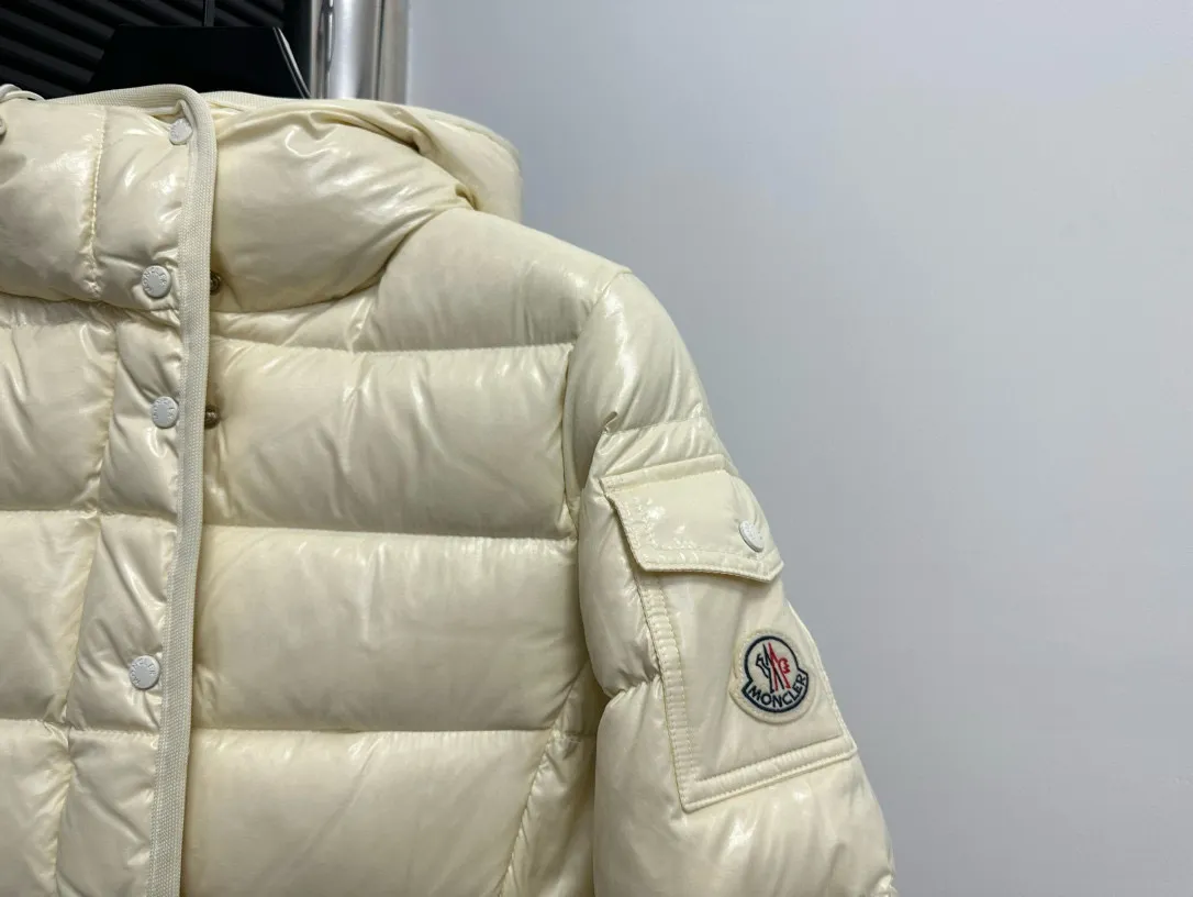 P860 [Moncler] Hooded, waisted women's short down jacket. The barante down jacket is made of glossy nylon fabric and is inspired by the 1970s. It adopts a waist design and presents an A-line silhouette, highlighting a feminine style. An adjustable hood and signature logo patch add finishing touches. Details · Made of lon laqué fabric · lon laqué lining · Filled with down · Adjustable hood · Zipper and snap closure · Suit pocket · Adjustable cuffs Size: 0/1/2/3