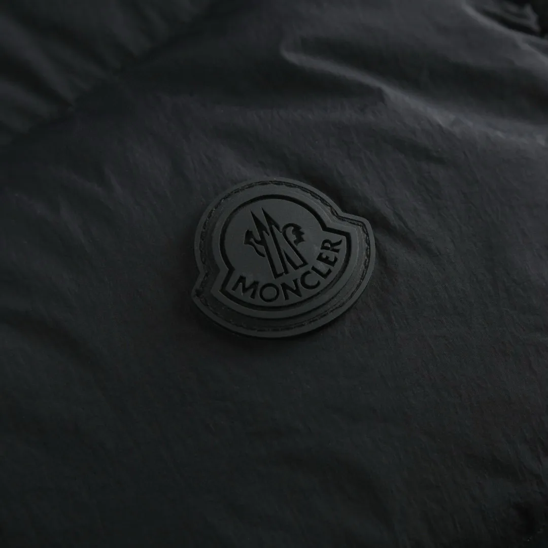 P680 Exclusive supply] Moncler Guersac Twill Quilted Hooded Down Vest (Black) The fabric is made of nylon fabric made of 100% nylon. It is woven into a tight and tough fabric through advanced textile technology, which improves the strength of the skeleton and effectively blocks the invasion of cold wind and locks in the warm air generated by the down layer. After tight weaving and special treatment, it has waterproof and windproof functions. The surface forms a certain lotus leaf effect, and is anti-wrinkle and not easy to deform, making it easy for daily care. Filled with 90% selected white duck down and weighing 170g, it ensures fluffiness, quick rebound, lightness and warmth. The quilting stitches are sewn in a diagonal direction at an angle of about 70 degrees, and the diagonal lines are arranged in parallel. The fabric and filling are planned into different functional areas, and the quilting stitches in each partition are relatively independent. This allows the finished product to produce a larger deformation space along the diagonal direction when stretched and pressed, making it less likely to tighten and break, and has rich visual effects, modern and advanced features. After the hood is removed, the stand-up collar displays an embossed logo of the same color, adding a unique visual experience and tactile details. Size:1-2-3-4