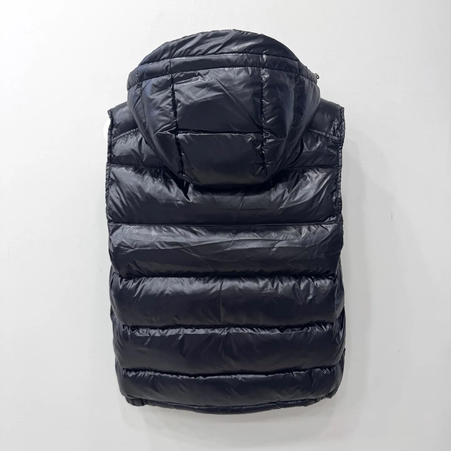 P580 Bormes Men's Hooded Down Vest] The Bormes men's vest is classic and timeless, with colors and details reminiscent of the Paninari trend of the 1980s.    The Bormes down vest is made from signature glossy nylon laqué fabric with classic checkered quilting for excellent warmth and protection. Two-way zipper closure design, with Moncler logo-shaped zipper puller.  • Made of nylon laqué • Nylon laqué lining • Filled with down • Detachable and adjustable hood • Collar with press buttons • Zipper closure • Zippered pockets • Fabric: 100% nylon; • Lining: 100% nylon; • Filling: Goose down • Down content: 90%; excluding upholstery; • Size: 12345 Maximum wash temperature 30°C - Gentle wash; Do not bleach; Do not tumble dry; Iron maximum temperature 110°C - without steam; Do not dry clean; Professional wet cleaning - gentle wash; Lay flat to dry in shade; Wash separately; Recommend washing and ironing inside out