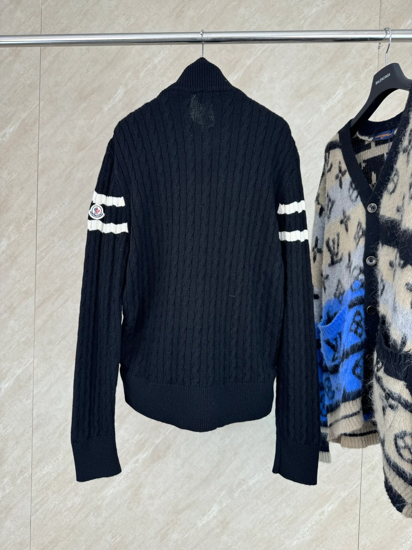 P810 Moncler Mouth Woolen Spliced ​​Down Jacket Size: 1 2 3 4 Fabric Selection: The outer front fabric is made of 100% nylon (nylon). Its high-density structure achieves excellent windproof effect. It also has strong wear resistance and wrinkle resistance. It is not afraid of scratches in daily wear and is easy to take care of.  The splicing design of sweaters and down jackets not only retains the thermal performance of down jackets, but also incorporates the fashion elements of sweaters, making the overall garment both practical and fashionable.  High-quality material: filled with high-quality white duck down, with a filling capacity of 100g, which has excellent thermal insulation effect. At the same time, the sweater is made of wool, cashmere and other natural fibers, which are soft, comfortable and skin-friendly.  The sweaters and down jackets are carefully spliced ​​to ensure comfortable wearing and are not prone to threading or velvet loss.  High collar design: not only provides excellent thermal insulation effect, but also adds a unique sense of fashion, allowing the wearer to maintain style in the cold season.  Stripe decoration: The stripes on the sleeve arms are like bright brush strokes, embellished on the dark gray down jacket, injecting vitality and movement into the overall look, making the clothing more eye-catching.  Accessories: one-to-one customized zipper puller, one-to-one customized armband