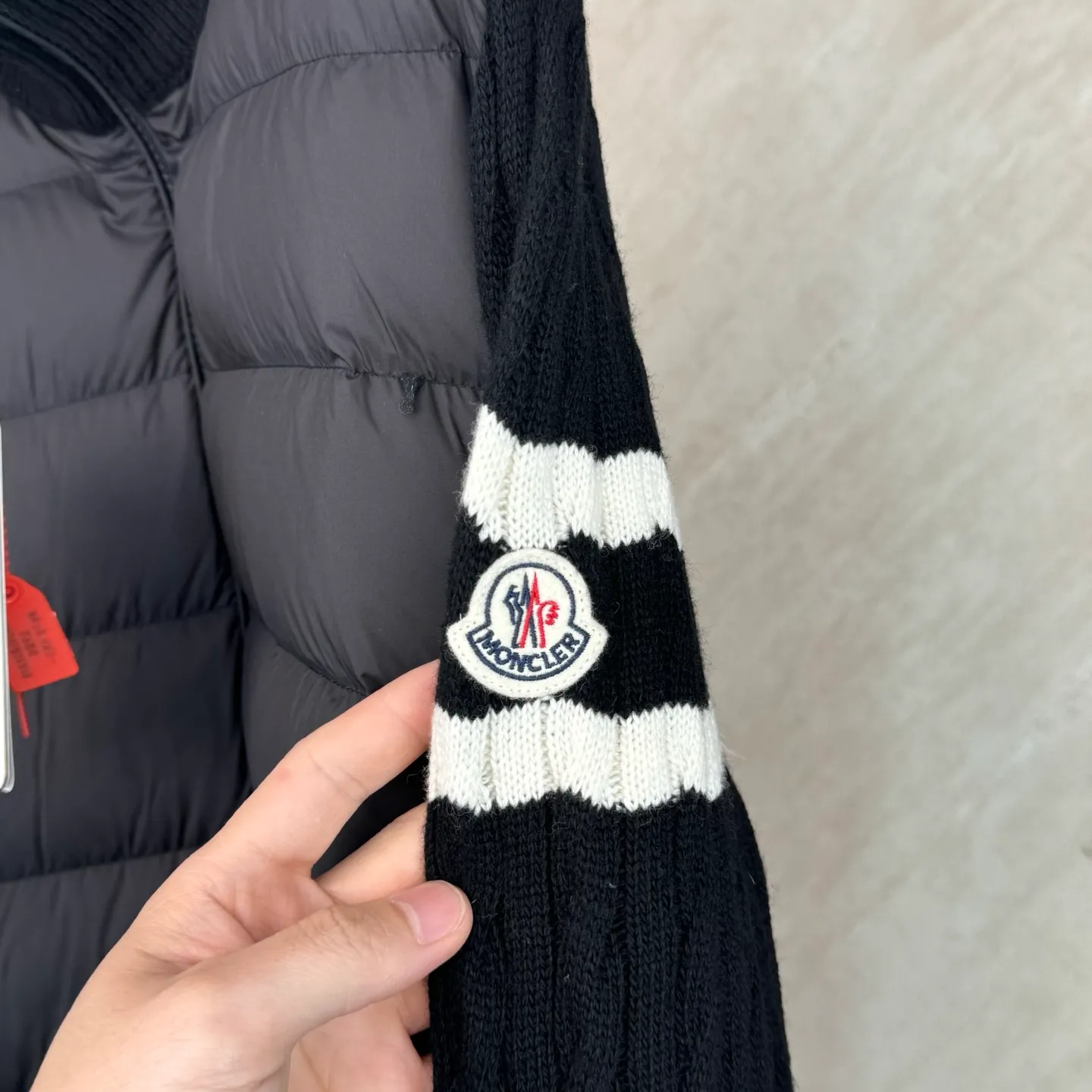P810 Moncler Mouth Woolen Spliced ​​Down Jacket Size: 1 2 3 4 Fabric Selection: The outer front fabric is made of 100% nylon (nylon). Its high-density structure achieves excellent windproof effect. It also has strong wear resistance and wrinkle resistance. It is not afraid of scratches in daily wear and is easy to take care of.  The splicing design of sweaters and down jackets not only retains the thermal performance of down jackets, but also incorporates the fashion elements of sweaters, making the overall garment both practical and fashionable.  High-quality material: filled with high-quality white duck down, with a filling capacity of 100g, which has excellent thermal insulation effect. At the same time, the sweater is made of wool, cashmere and other natural fibers, which are soft, comfortable and skin-friendly.  The sweaters and down jackets are carefully spliced ​​to ensure comfortable wearing and are not prone to threading or velvet loss.  High collar design: not only provides excellent thermal insulation effect, but also adds a unique sense of fashion, allowing the wearer to maintain style in the cold season.  Stripe decoration: The stripes on the sleeve arms are like bright brush strokes, embellished on the dark gray down jacket, injecting vitality and movement into the overall look, making the clothing more eye-catching.  Accessories: one-to-one customized zipper puller, one-to-one customized armband