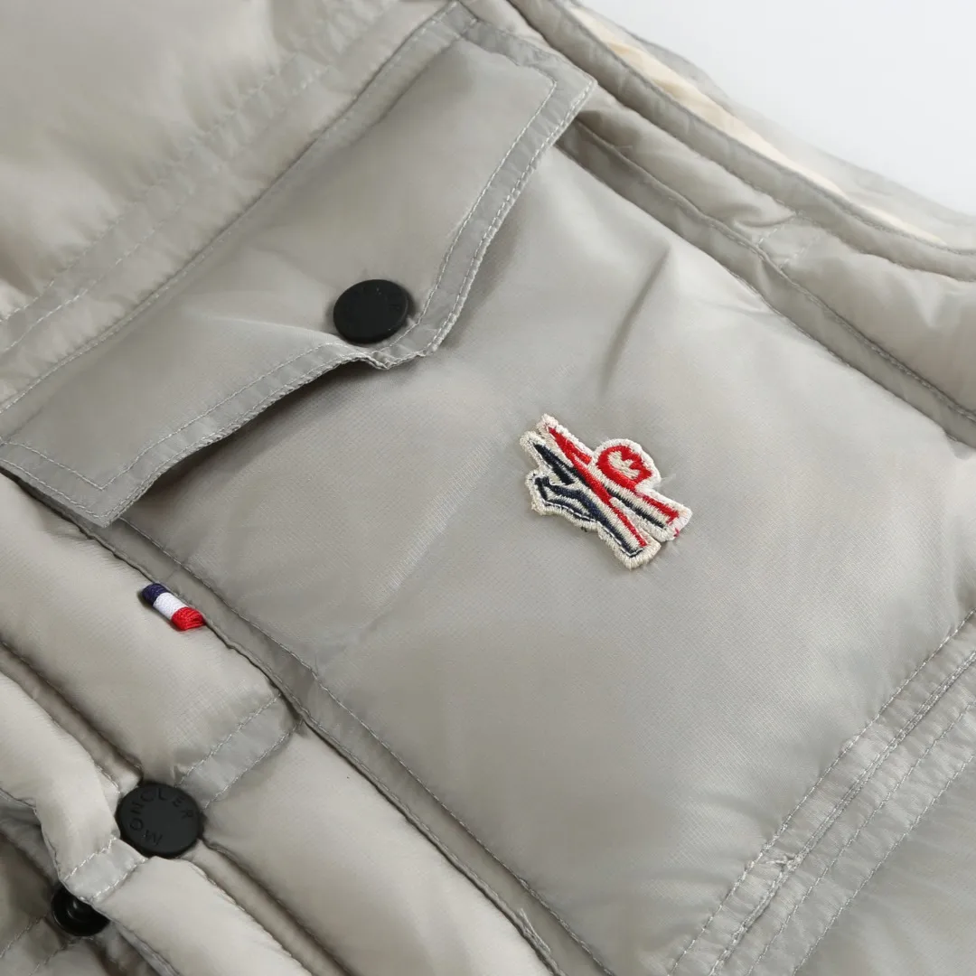 P680 MONCLER down vest with reflective markings Fabric selection: Made of ultra-fine nylon yarn woven in a high-density manner. The number of yarns per unit area is large, and the gaps between the yarns are very small, which can effectively block the penetration of cold wind. The fine weave keeps it lightweight and soft to the touch, physically restricting the lightweight down fibers from slipping through the gaps. Nylon fiber itself has good wear resistance and is not easy to snag, which significantly extends its service life and can easily cope with the needs of multiple scenarios.  Lining selection: The lining is made of 100% polyester fiber high-density weaving. The thickness of 0.08mm avoids increasing the overall weight and makes it smooth to wear. The high-density weaving structure forms a wind resistance layer to protect the thermal efficiency of the thermal insulation layer from loss. At the same time, it can withstand the expansion pressure of down and prevent deformation and damage after long-term use.  High-quality filling: 90 white duck down is selected, with a weight of 130g, ensuring excellent thermal insulation performance. After strict screening and processing, the velvet is not easy to get drilled, ensuring durability.  Process: Through the reflective cloth punching process, the logo is regularly arranged on the triangular reflective mark with dozens of small holes, which not only improves the functionality, but also strengthens the recognition and aesthetics.   Accessories: One-to-one customized snap buttons, one-to-one customized zipper pullers, one-to-one customized badges, one-to-one customized elastic buckles, etc. SIZE: 1 2 3 4