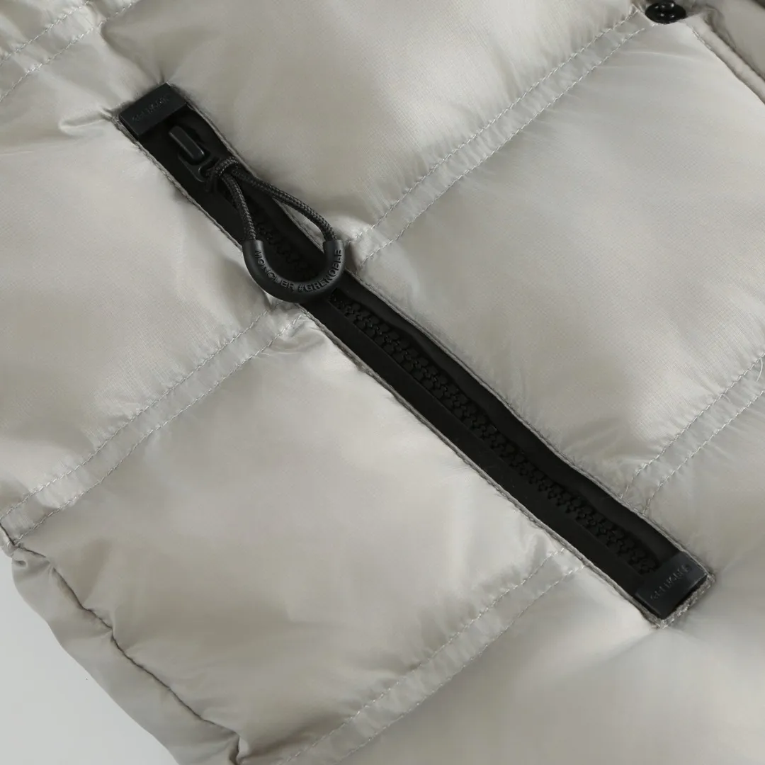 P680 MONCLER down vest with reflective markings Fabric selection: Made of ultra-fine nylon yarn woven in a high-density manner. The number of yarns per unit area is large, and the gaps between the yarns are very small, which can effectively block the penetration of cold wind. The fine weave keeps it lightweight and soft to the touch, physically restricting the lightweight down fibers from slipping through the gaps. Nylon fiber itself has good wear resistance and is not easy to snag, which significantly extends its service life and can easily cope with the needs of multiple scenarios.  Lining selection: The lining is made of 100% polyester fiber high-density weaving. The thickness of 0.08mm avoids increasing the overall weight and makes it smooth to wear. The high-density weaving structure forms a wind resistance layer to protect the thermal efficiency of the thermal insulation layer from loss. At the same time, it can withstand the expansion pressure of down and prevent deformation and damage after long-term use.  High-quality filling: 90 white duck down is selected, with a weight of 130g, ensuring excellent thermal insulation performance. After strict screening and processing, the velvet is not easy to get drilled, ensuring durability.  Process: Through the reflective cloth punching process, the logo is regularly arranged on the triangular reflective mark with dozens of small holes, which not only improves the functionality, but also strengthens the recognition and aesthetics.   Accessories: One-to-one customized snap buttons, one-to-one customized zipper pullers, one-to-one customized badges, one-to-one customized elastic buckles, etc. SIZE: 1 2 3 4