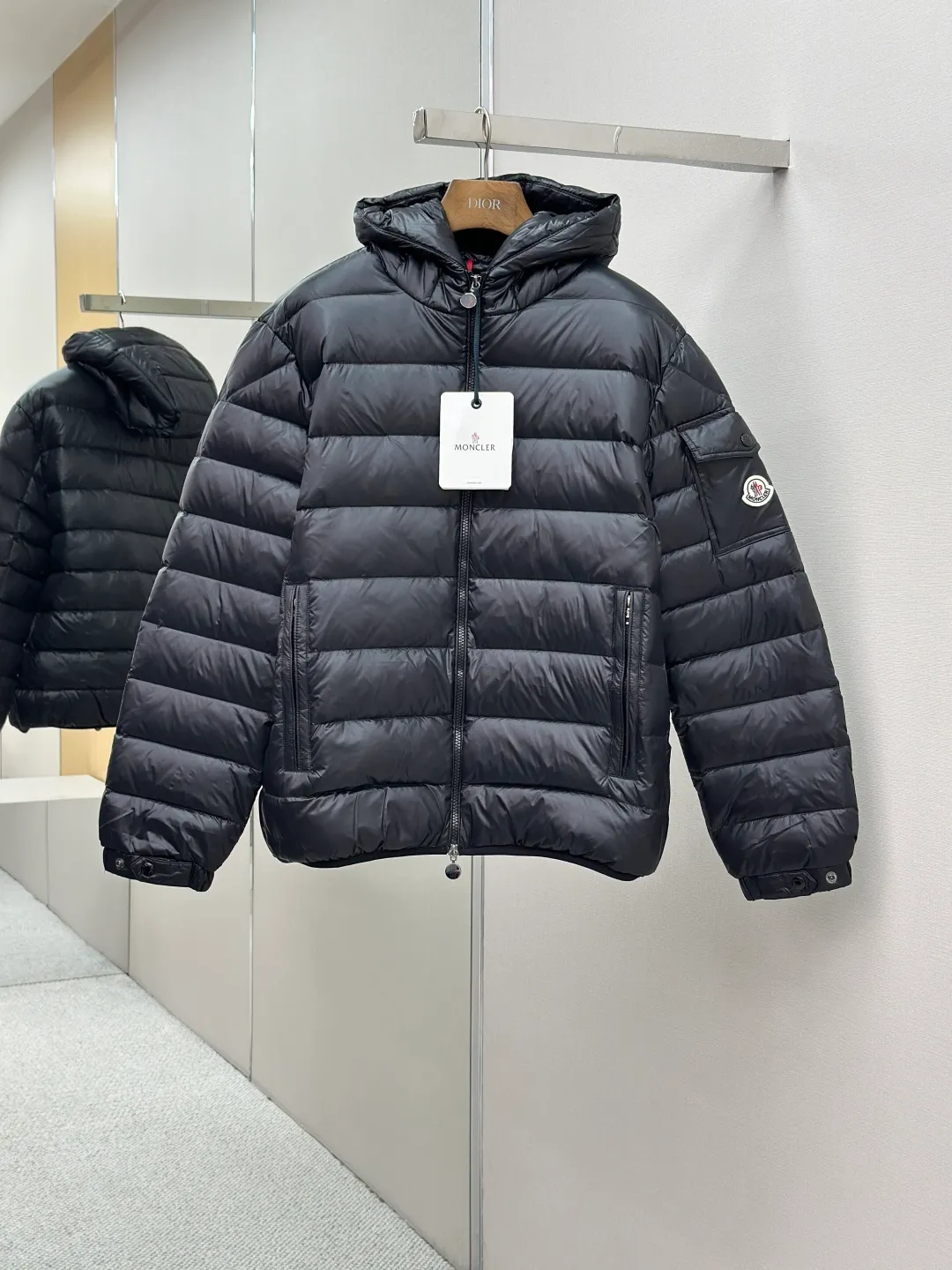 P910 MONCLER hooded brim quilted embroidered down jacket Fabric selection: The longue saison fabric is made of high-count polyamide fiber, which is known for its excellent tensile strength and lightness. Its good flexibility makes the fabric less prone to wrinkles and keeps it crisp and stylish for a long time. The tight weave effectively blocks the invasion of cold wind and locks in the warm air generated by the down layer. The high-density nylon surface forms a certain lotus leaf effect, making it difficult for small water droplets to penetrate, keeping the interior dry and effectively extending the service life of the down.  Lining selection: High-density lining fabric made of ultra-fine denier, 0.08mm thickness to avoid increasing the overall weight and making it smooth to wear. The high-density woven structure forms a wind resistance layer to protect the thermal efficiency of the thermal layer from loss. It can also withstand the expansion pressure of down and prevent deformation and damage after long-term use.  Technology: The quilted letter logo on the brim uses contour quilting technology. The stitching is routed along the edge of the set outline, and the filler is compressed inside the letter graphic, so that the logo is three-dimensional and convex, and the pattern is clear.  High-quality filling: It is filled with 90% selected white duck down, weighing 210g, ensuring fluffy rebound, lightness and warmth.  Accessories: customized zipper pendant, customized badge, customized three-label SIZE: 1 2 3 4