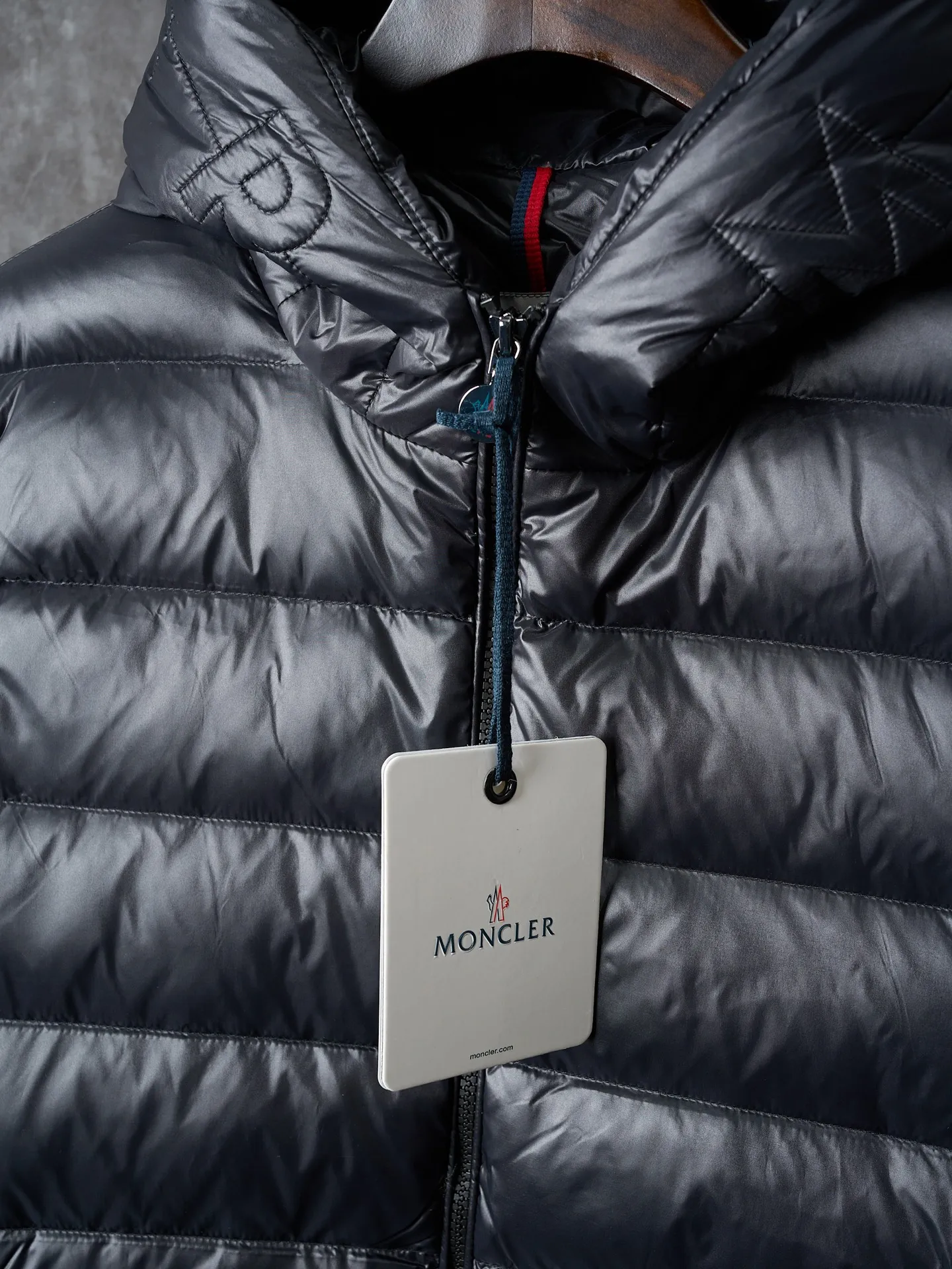 P900 Actual hanging auction] MONCLER/Maskled brim quilted embroidered pocket logo hooded down jacket [Ready stock] 1 2 3 4 Filled with 90 selected white duck down, weighing 210g, ensuring fast fluffy rebound, lightness and warmth.  The longue saison fabric made of high-count polyamide fiber is famous for its excellent tensile strength and lightness. Its good flexibility makes the fabric less prone to wrinkles and keeps it crisp and stylish for a long time. The tight weave effectively blocks the invasion of cold wind and locks in the warm air generated by the down layer. The high-density nylon surface forms a certain lotus leaf effect, making it difficult for small water droplets to penetrate, keeping the interior dry and effectively extending the service life of the down.  The high-density lining is woven with ultra-fine denier, with a thickness of 0.08mm to avoid increasing the overall weight and making it smooth to wear. The high-density woven structure forms a wind resistance layer to protect the thermal efficiency of the thermal layer from loss. It can also withstand the expansion pressure of down and prevent deformation and damage after long-term use.  The quilted letter logo on the brim uses contour quilting technology. The stitches are routed along the edge of the set outline, and the filler is compressed inside the letter graphic, so that the logo is three-dimensional and the pattern is clear.
