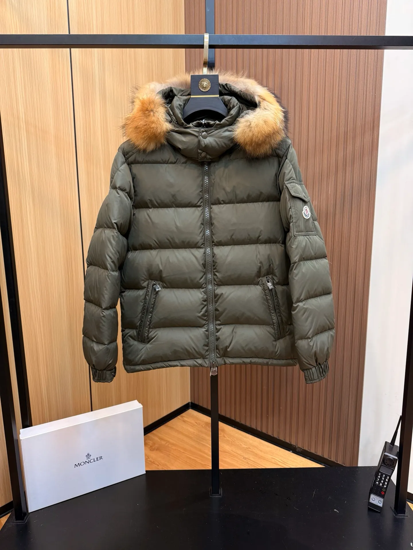 P1040 Moncler Mayaf short men's down jacket. The hood is removable. The fur collar is removable. Based on Maya, a removable fur collar is added. The Mayaf men's hooded down jacket is made of functional nylon fabric, and the hood is equipped with removable synthetic material trim.  The Mayaf short down jacket is a reinterpretation of the classic Moncler Maya style in an instantly recognizable silhouette, with a removable hood and adjustable hem. Made from functional fabric with removable synthetic trim on the hood. The sleeves are embellished with classic patch pockets, reflecting the brand's signature style. Details •Made from functional fabric •Technical fabric lining •Down-filled •Push-stud collar •Detachable hood with removable synthetic trim •Zip closure •Zip pockets •Patch pockets with press-stud •Adjustable elastic cuffs •Adjustable drawstring hem