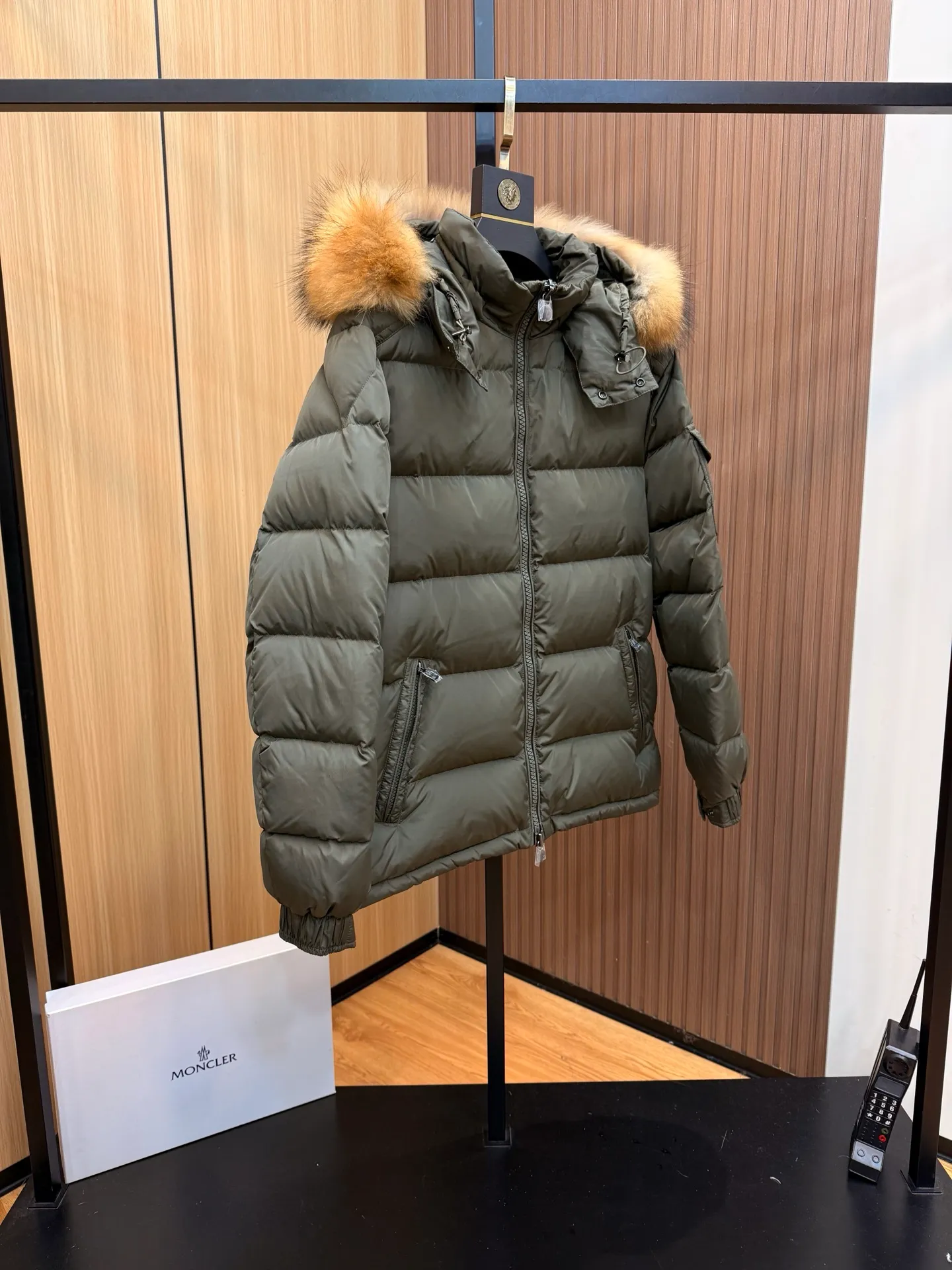 P1040 Moncler Mayaf short men's down jacket. The hood is removable. The fur collar is removable. Based on Maya, a removable fur collar is added. The Mayaf men's hooded down jacket is made of functional nylon fabric, and the hood is equipped with removable synthetic material trim.  The Mayaf short down jacket is a reinterpretation of the classic Moncler Maya style in an instantly recognizable silhouette, with a removable hood and adjustable hem. Made from functional fabric with removable synthetic trim on the hood. The sleeves are embellished with classic patch pockets, reflecting the brand's signature style. Details •Made from functional fabric •Technical fabric lining •Down-filled •Push-stud collar •Detachable hood with removable synthetic trim •Zip closure •Zip pockets •Patch pockets with press-stud •Adjustable elastic cuffs •Adjustable drawstring hem