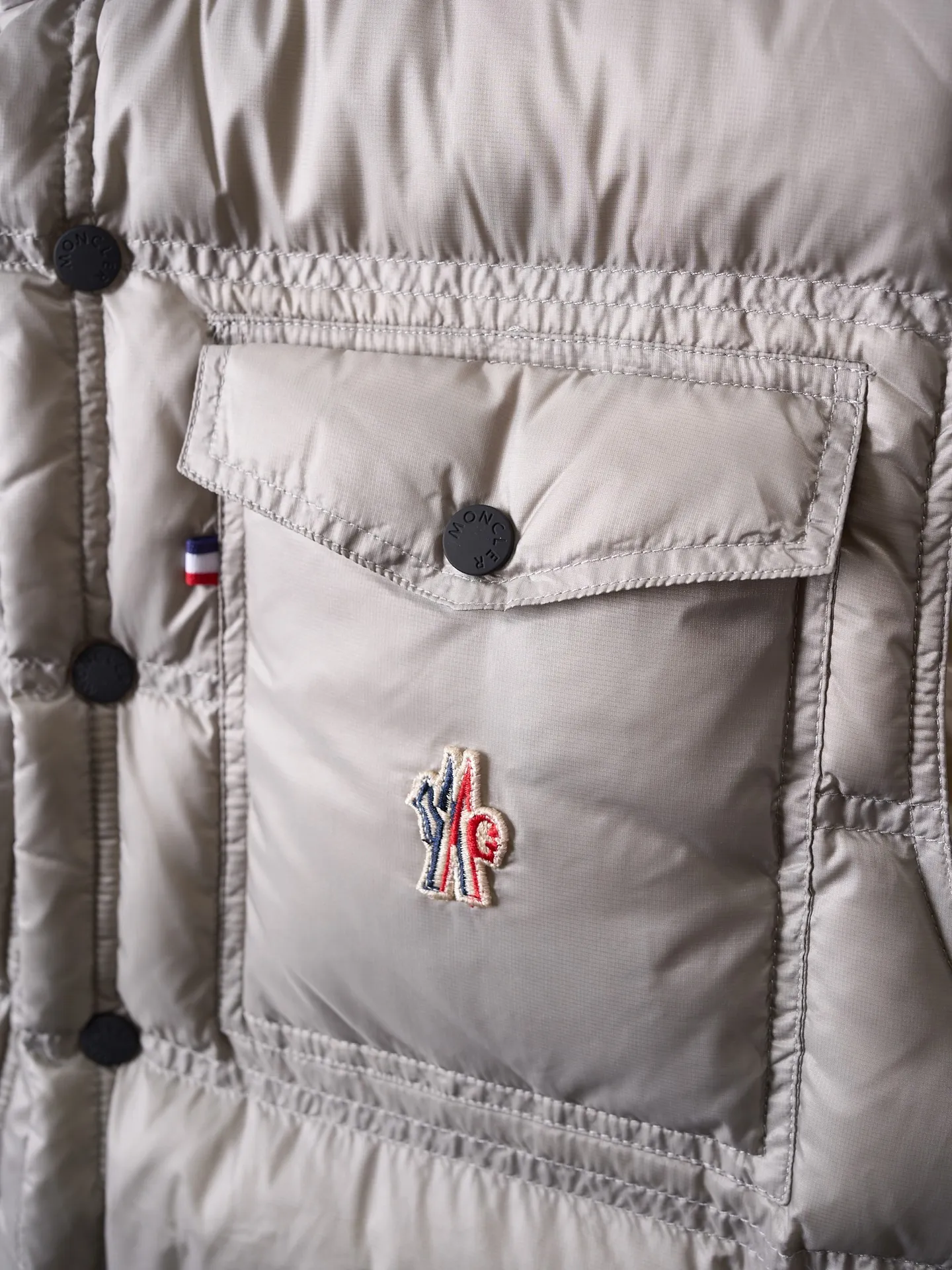 P680 Actual hanging auction] MONCLER/Mandow embroidered reflective logo stand-up collar down vest [Ready stock] 1 2 3 4 It is made of extremely fine nylon yarn and woven in a high-density way. The number of yarns per unit area is large, and the gaps between the yarns are very small, which can effectively block the penetration of cold wind. The fine weave keeps it lightweight and soft to the touch, physically restricting the lightweight down fibers from slipping through the gaps. Nylon fiber itself has good wear resistance and is not easy to snag, which significantly extends its service life and can easily cope with the needs of multiple scenarios.  The lining is made of high-density weaving of 100% polyester fiber, with a thickness of 0.08mm to avoid increasing the overall weight and making it smooth to wear. The high-density weaving structure forms a wind resistance layer to protect the thermal efficiency of the thermal layer from loss. It can withstand the expansion pressure of down and prevent deformation and damage after long-term use.  It uses 90 white duck down with a weight of 130g to ensure excellent thermal insulation performance. After strict screening and processing, the velvet is not easy to get drilled, ensuring durability.  Through the reflective cloth punching process, the logo is regularly arranged on the triangular reflective mark with dozens of small holes, which not only improves functionality but also enhances recognition and aesthetics.