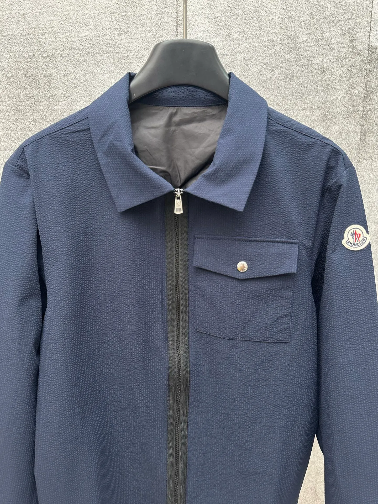 P440 MONCLER bubble wrinkle shirt jacket Fabric selection: Made of cotton blended woven fabric with 76% high cotton content + 24% polyester fiber. The high cotton content ensures that the fabric is soft, skin-friendly, and has good breathability. The addition of a small amount of polyester fiber balances the wrinkle resistance and elasticity of the overall fabric and greatly reduces its shrinkage. After preshrinking, dimensional changes during washing are negligible. The fusion of the two makes the fabric combine anti-wrinkle, quick-drying, easy care and other characteristics without losing the advantages of good wearing experience and strong breathability.  Bubble wrinkle technology: ground warp + bubble warp independent let-off. The bubble warp yarn feeding speed is about 20% higher than the ground warp yarn feeding speed. During weaving, the bubble warp is relaxed and accumulated, forming a naturally arched bubble unit. Through the alternating arrangement of yarns + floating length tissue changes, a clear grid frame is built between the bubble units, and finally the bubble three-dimensional effect and grid outline are locked through high-temperature heat setting.  Accessories: One-to-one customized zipper puller, one-to-one customized LOGO armband, one-to-one customized snap button SIZE: 1 2 3 4